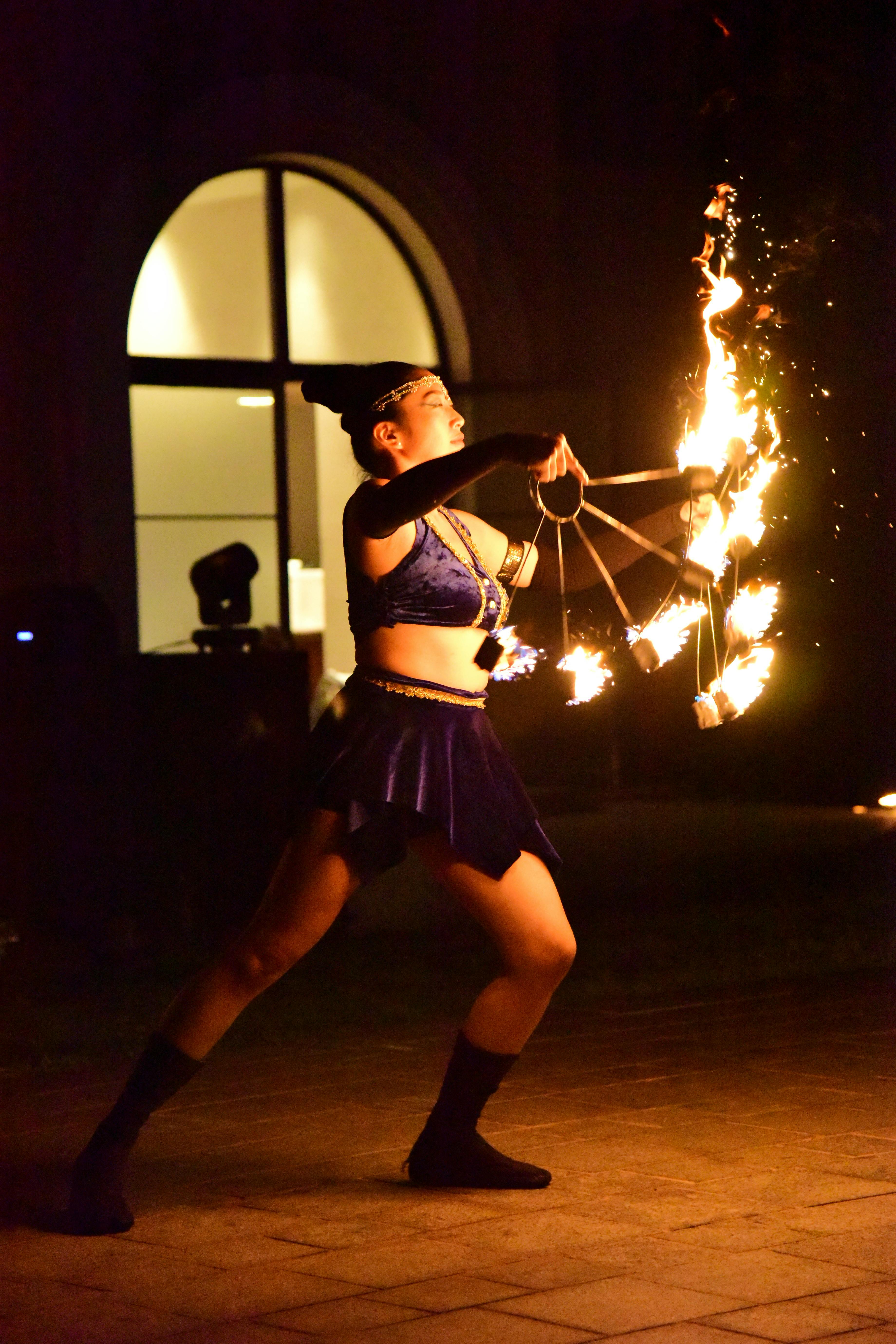 A captivating fire dancer performing with flames at night outdoors.
