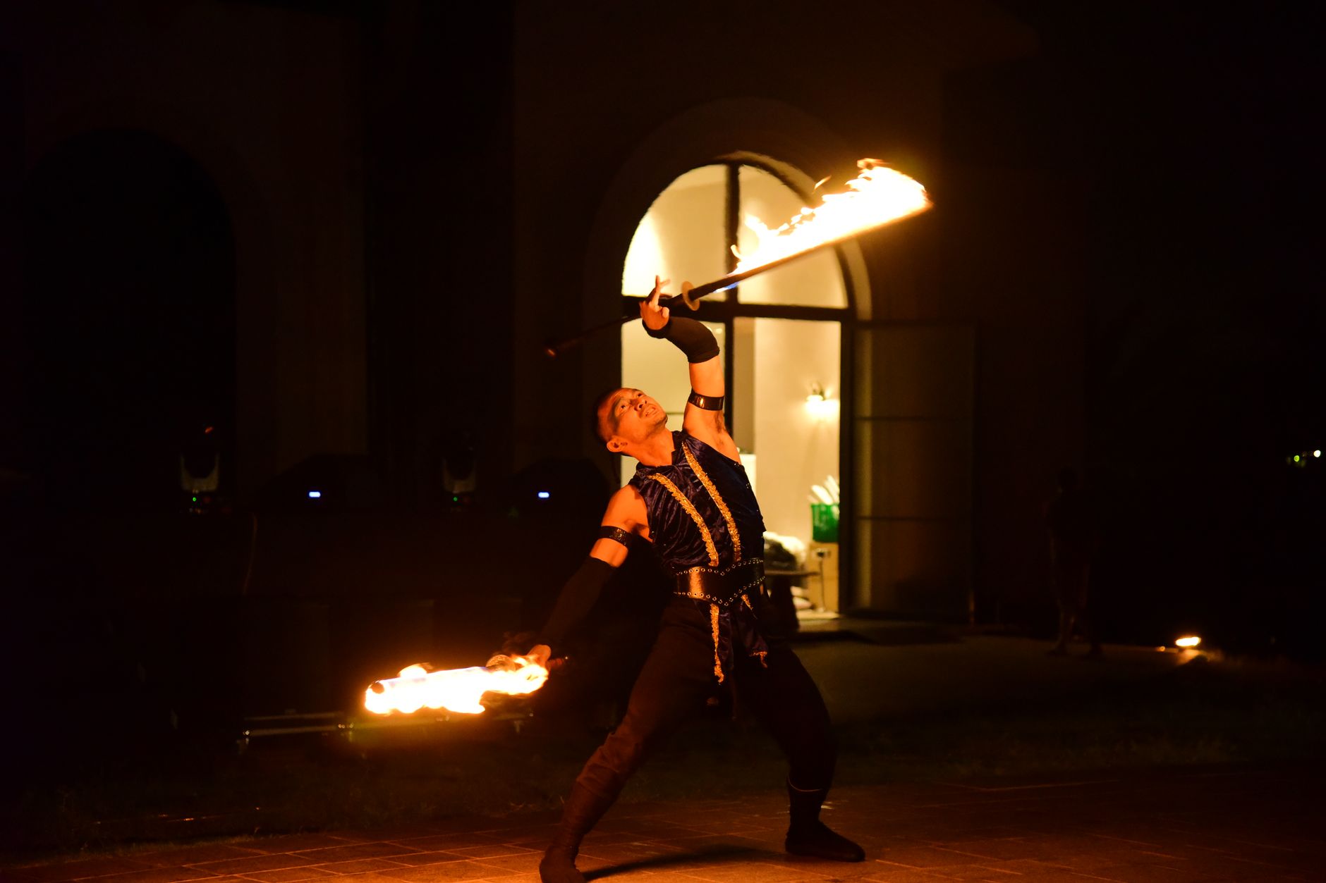Dynamic fire performer dancing with flames in a nighttime spectacle.