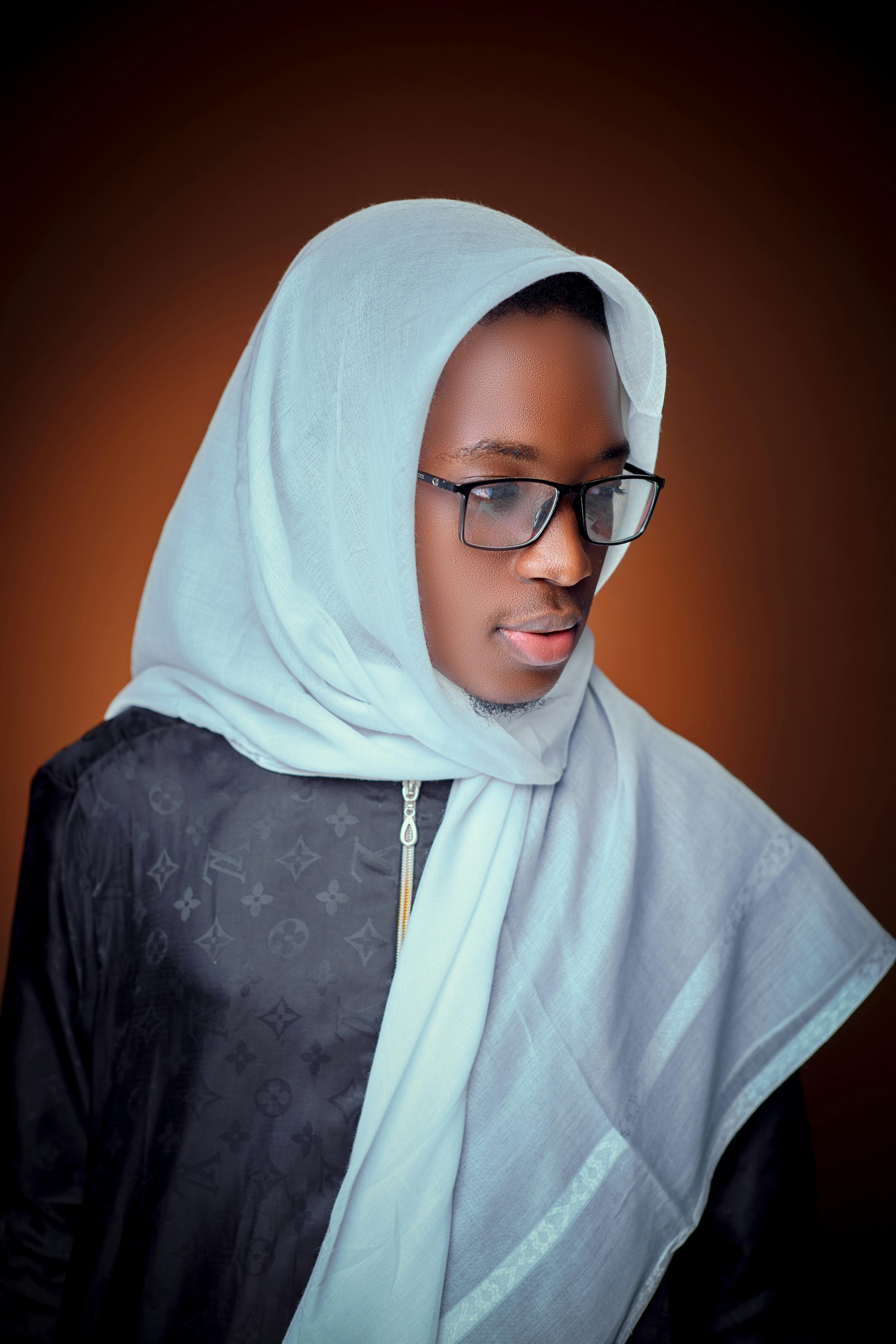 Gratis Seorang pemuda berkacamata dan mengenakan jilbab, berpose dengan ekspresi percaya diri. Foto Stok