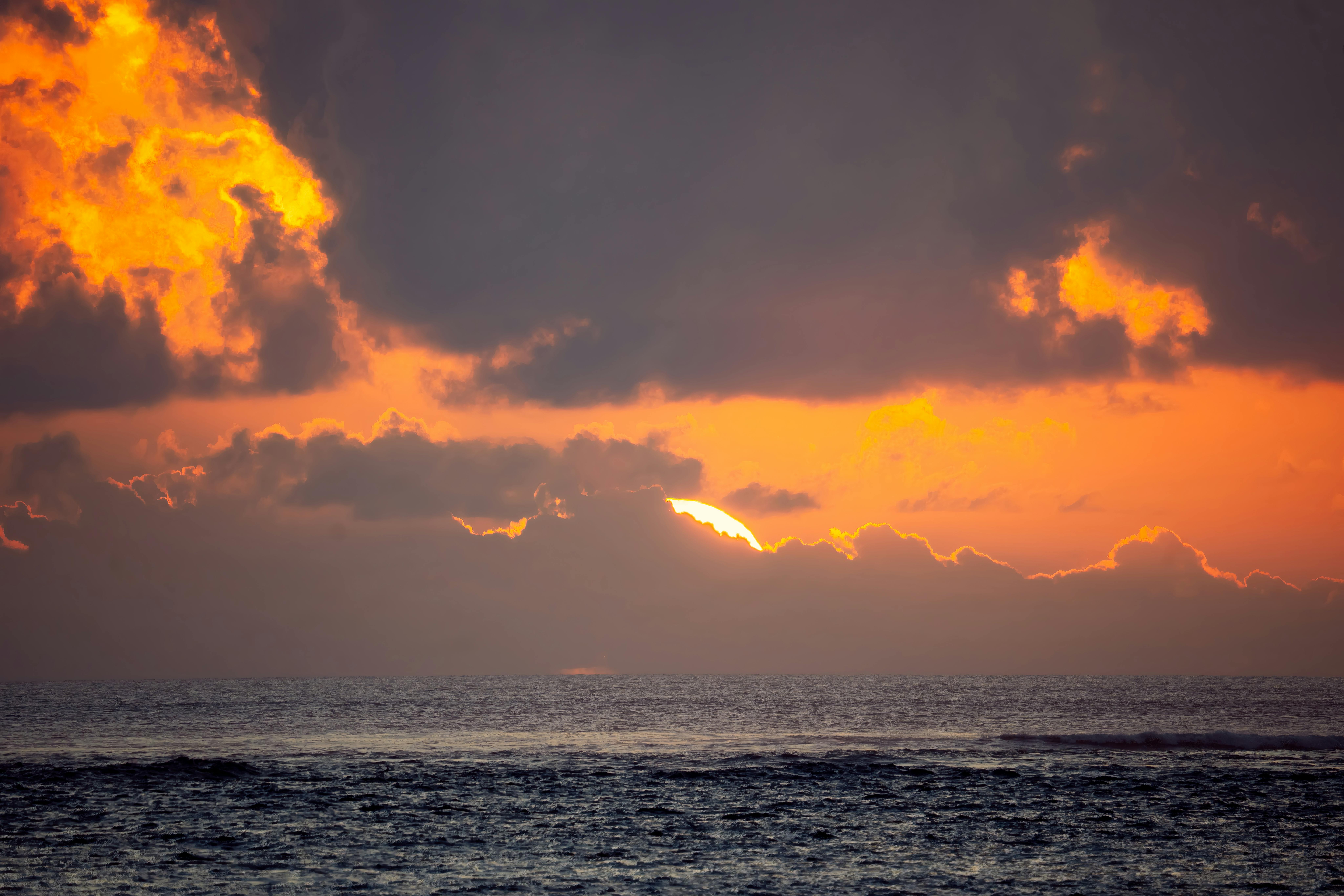 Gratis Pemandangan matahari terbenam yang memukau di atas laut di Bali, memperlihatkan nuansa oranye dan ungu yang cerah. Foto Stok