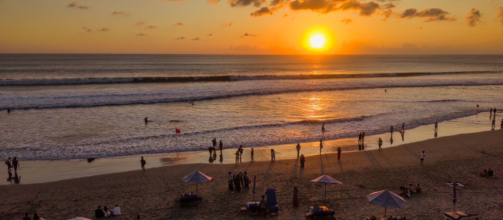 People enjoying a vibrant sunset at Kuta Beach, Bali. Perfect for travel and leisure themes.
