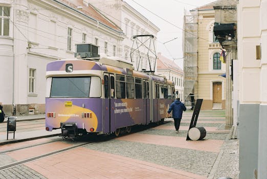 Vibrant city tram in a European urban street with historic architecture.