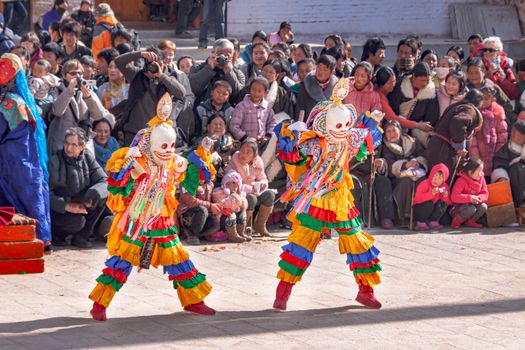 Vibrant traditional Tibetan dance with masked performers and a captivated crowd in Qinghai, China.