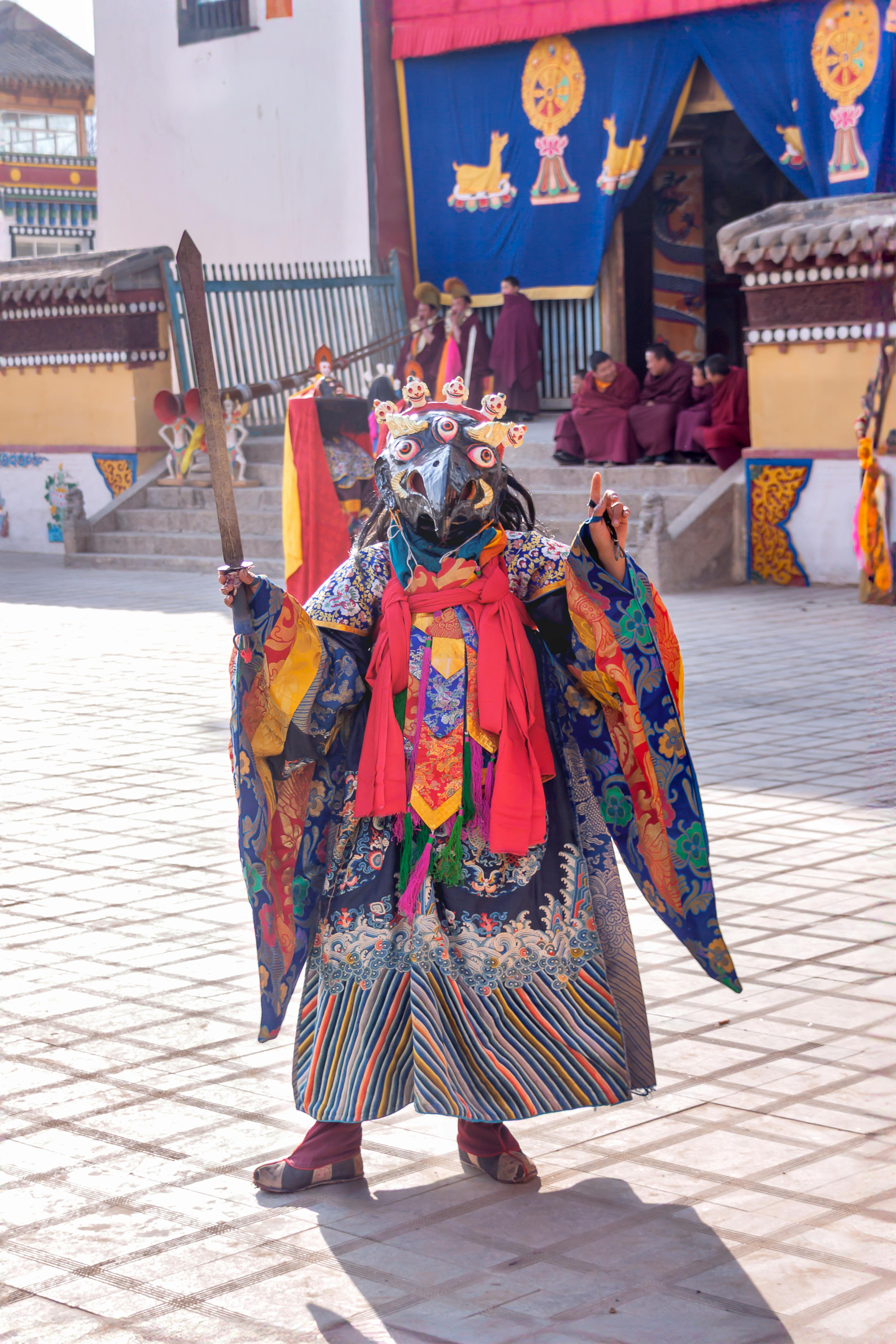 Colorful Tibetan mask dancer performing in Huangnan, Qinghai, during a cultural festival.