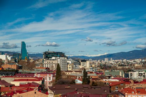 Free Dynamic aerial view of Tbilisi, Georgia showcasing modern and classic architecture against a mountainous backdrop. Stock Photo