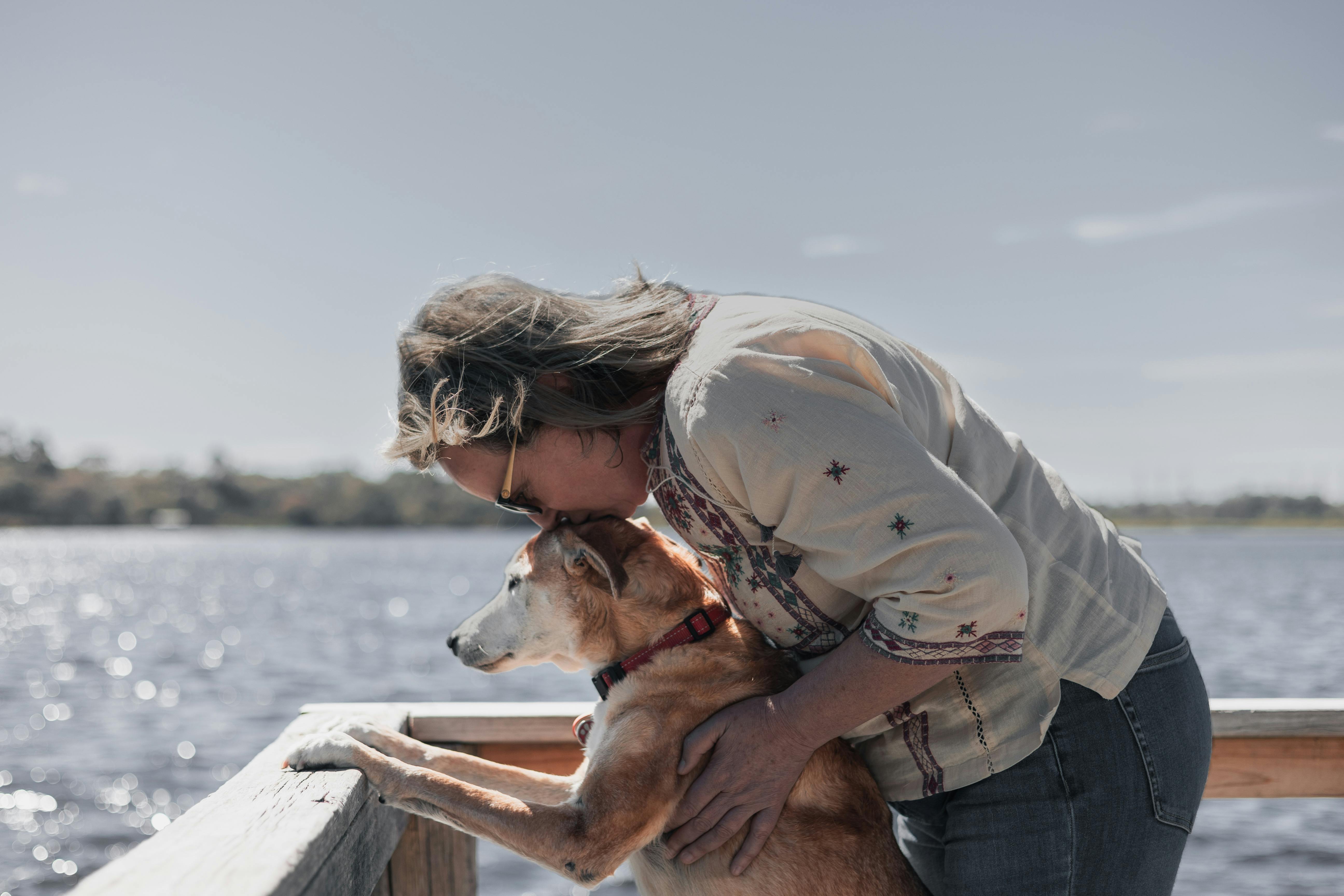 A woman lovingly embraces her pet dog by Bibra Lake, Western Australia.