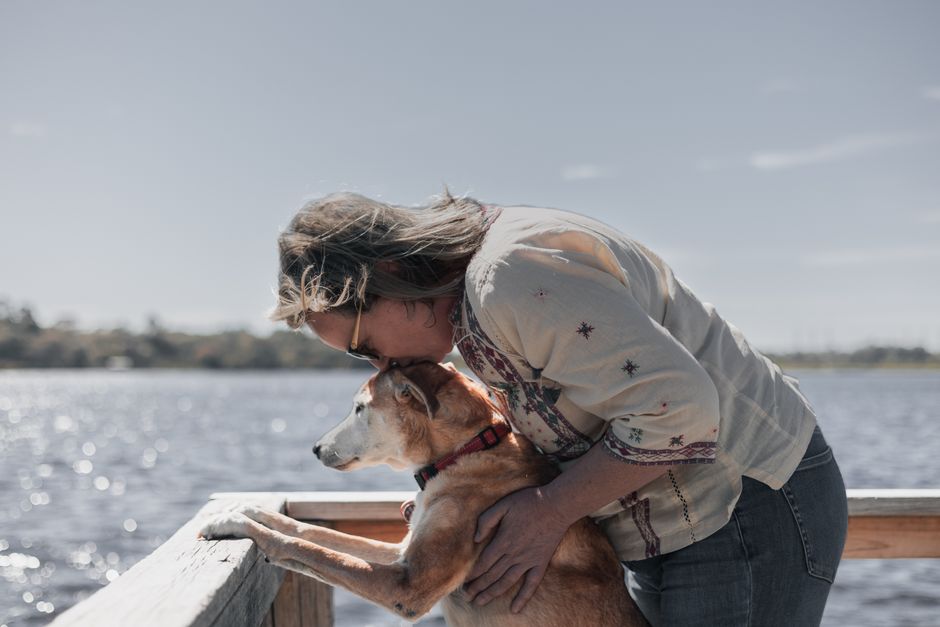 A woman lovingly embraces her pet dog by Bibra Lake, Western Australia.