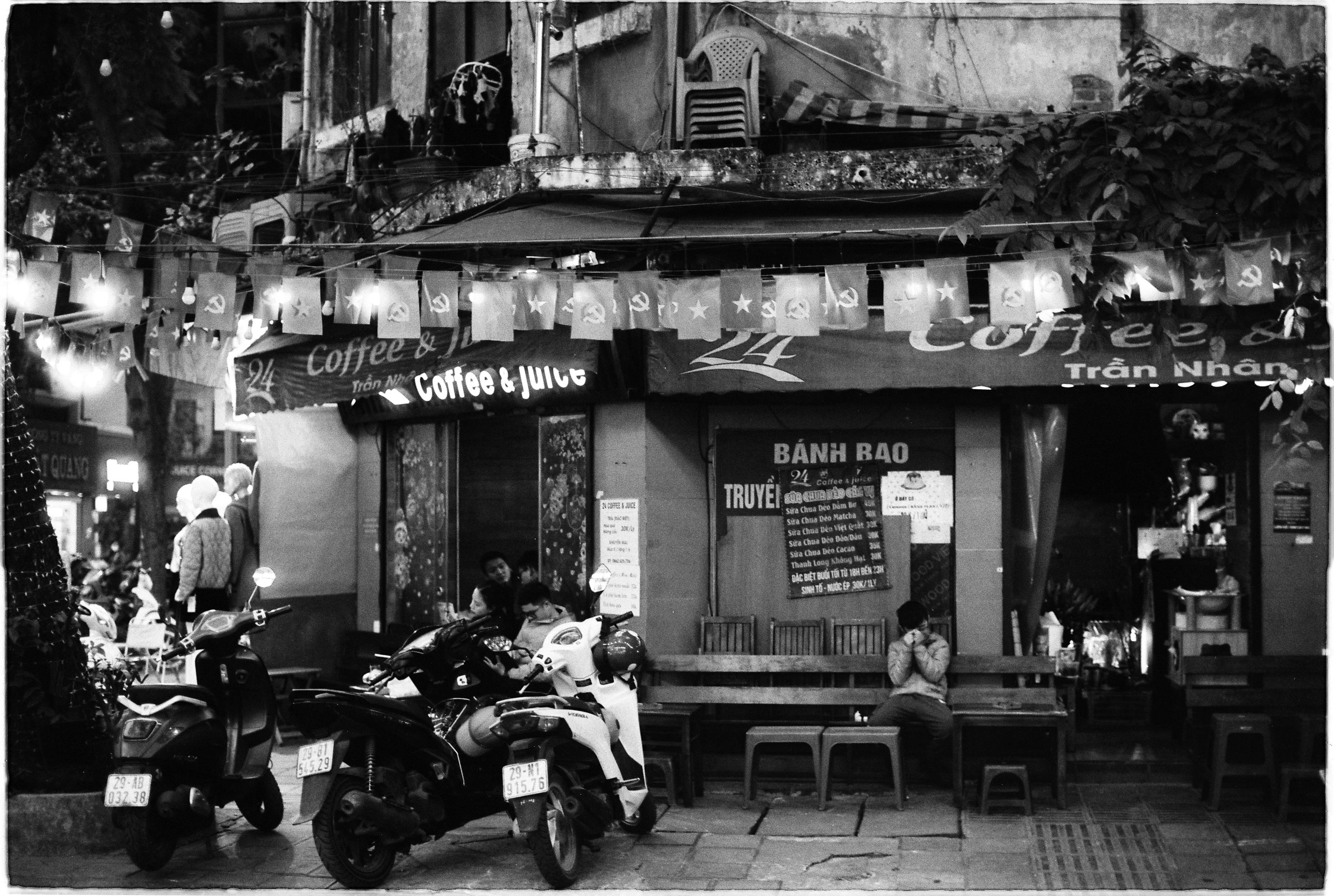 Black and white photo depicting a vibrant Hanoi street with scooters and people.