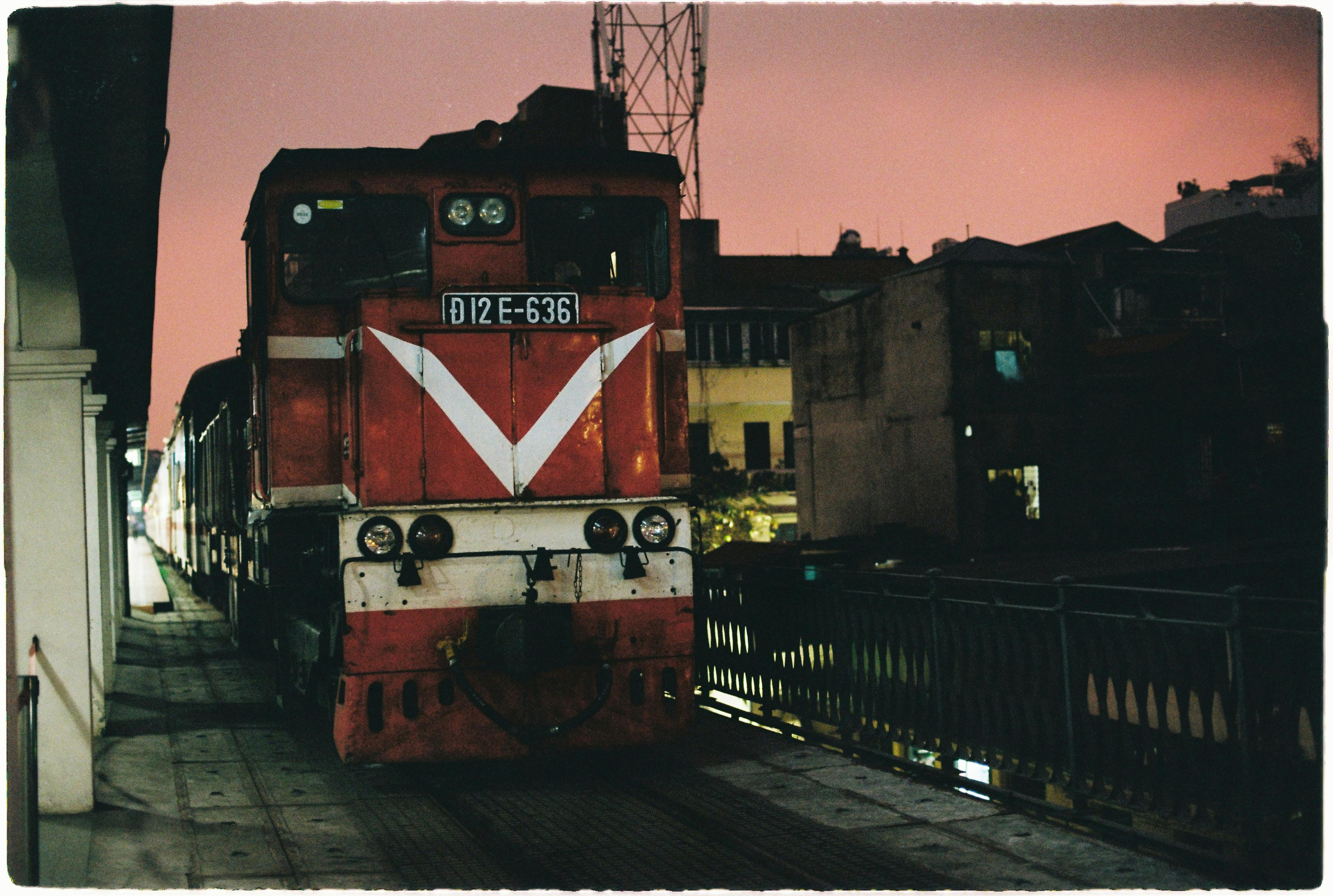 A red train locomotive at night in Hanoi, Vietnam, showcasing urban transportation.