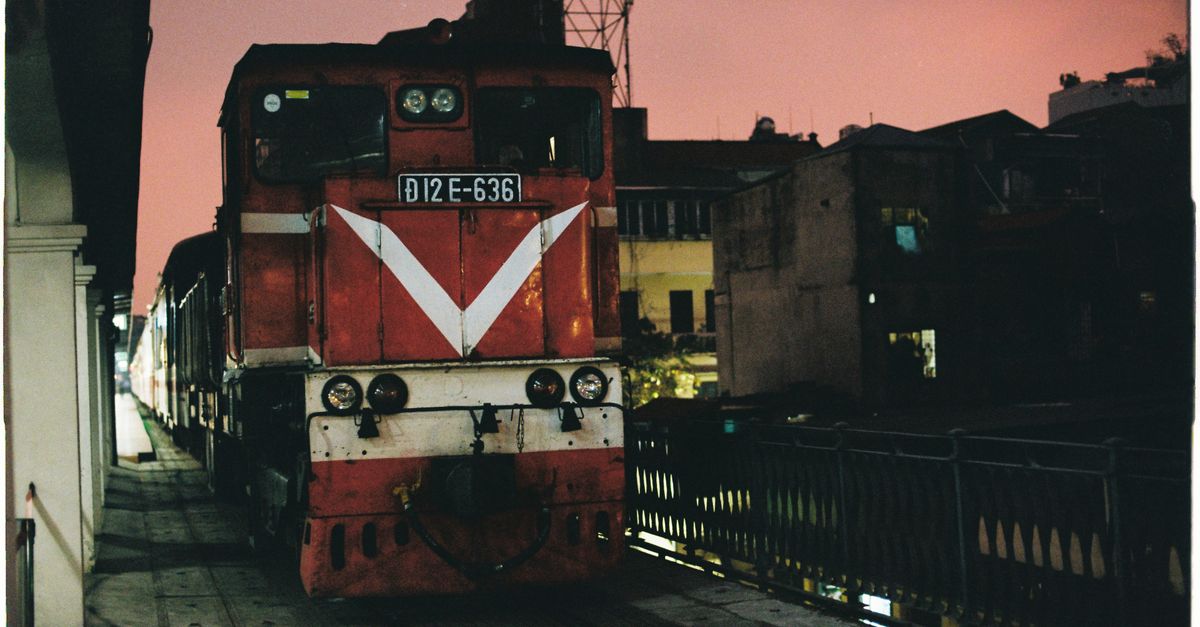 A red train locomotive at night in Hanoi, Vietnam, showcasing urban transportation.