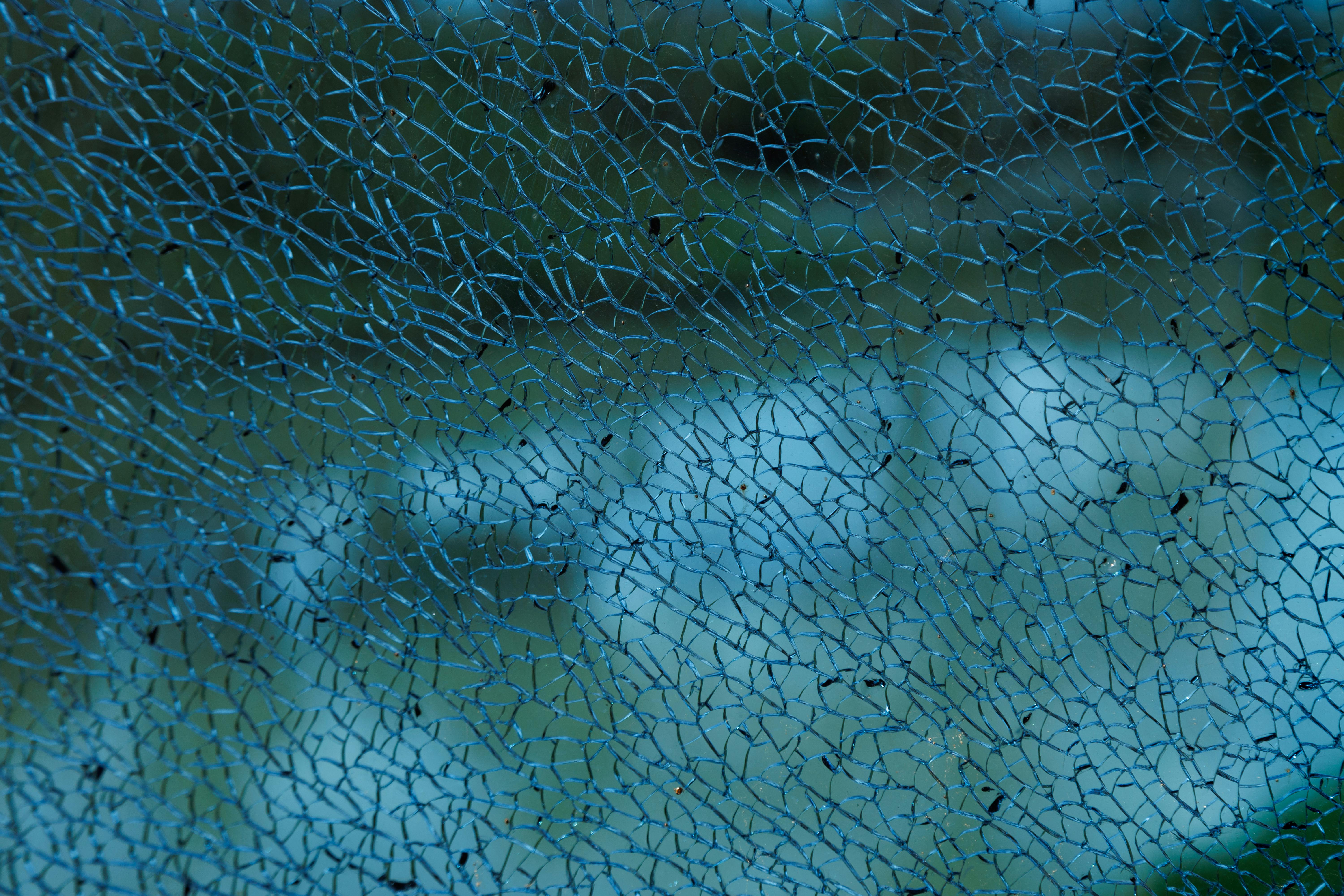 Free Detailed close-up image of shattered glass with intricate blue pattern against blurry background. Stock Photo