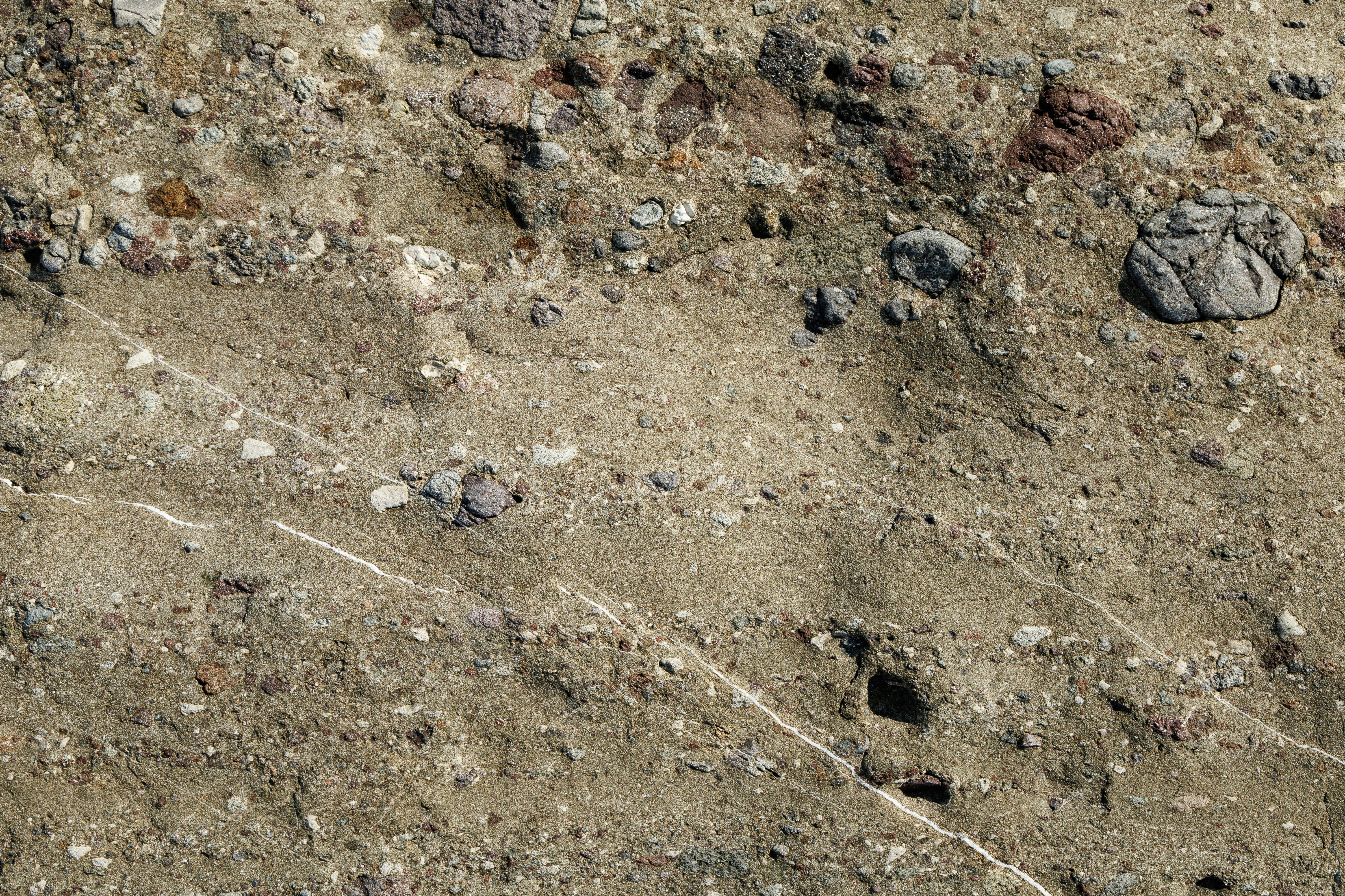 Free Detailed view of a sedimentary rock surface showcasing varied textures and embedded stones. Stock Photo