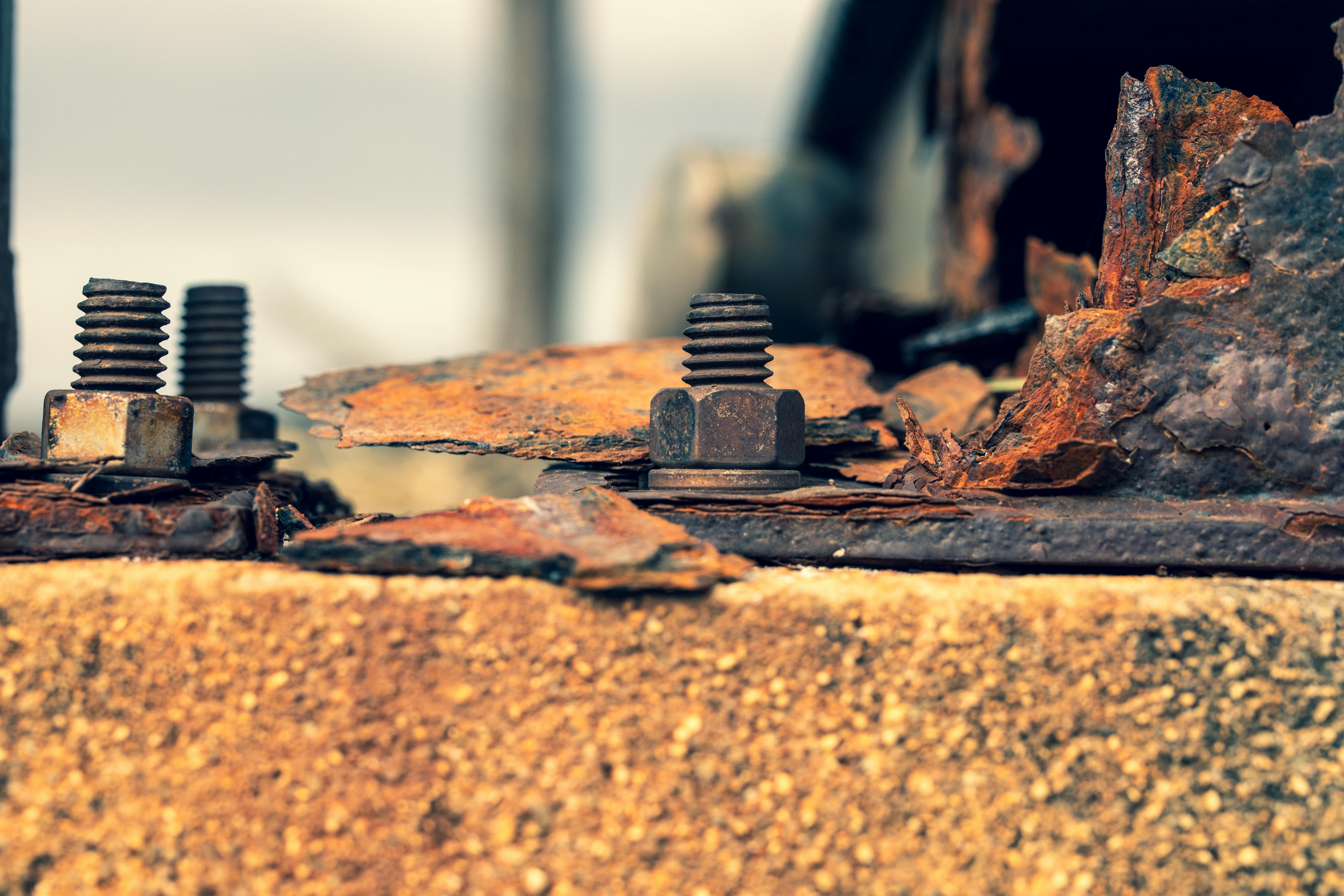 бесплатная Детальный снимок ржавых винтов на корродированной металлической поверхности, демонстрирующий признаки разрушения. Стоковое фото