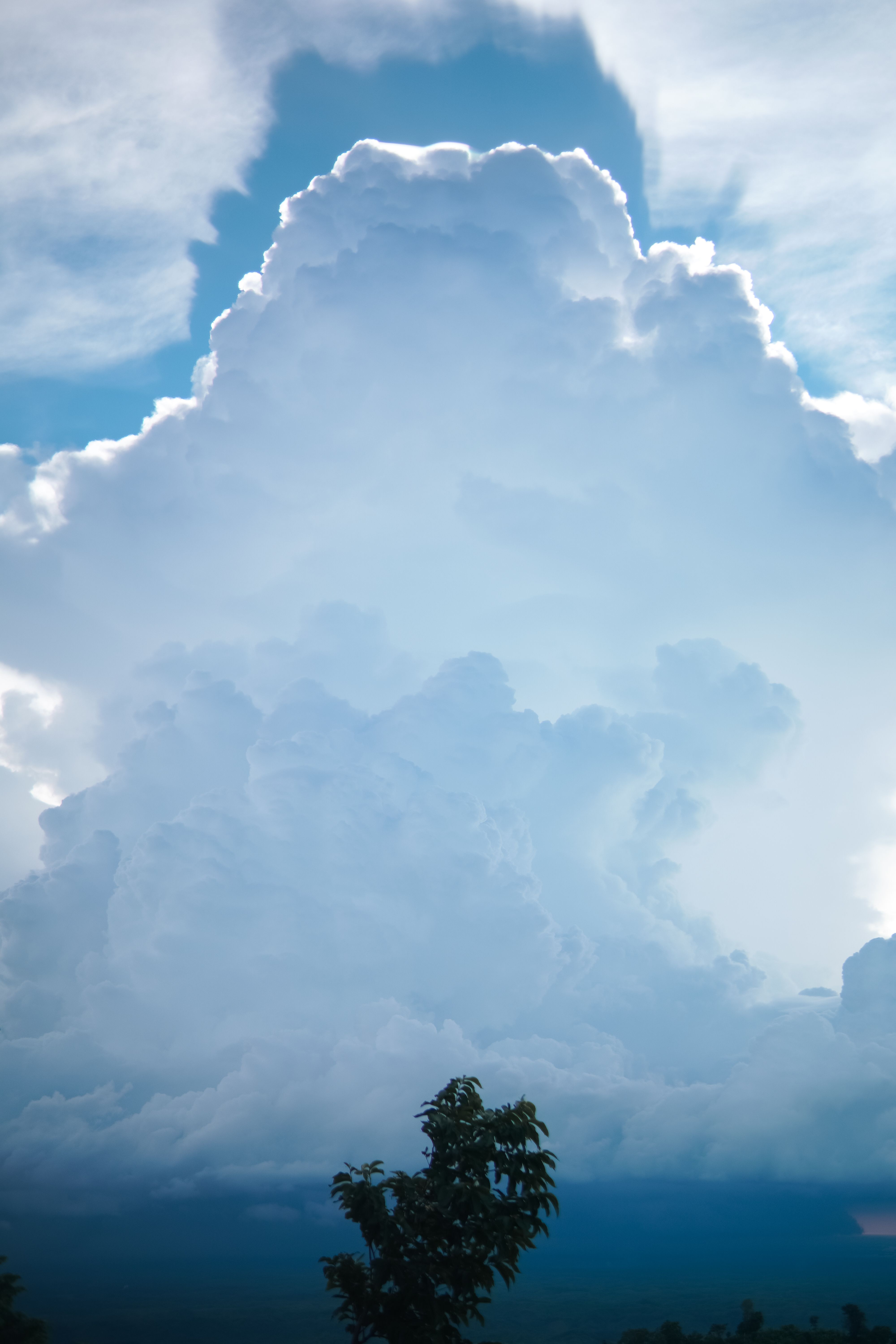 A towering cumulonimbus cloud under a bright blue sky, creating a dramatic atmosphere.