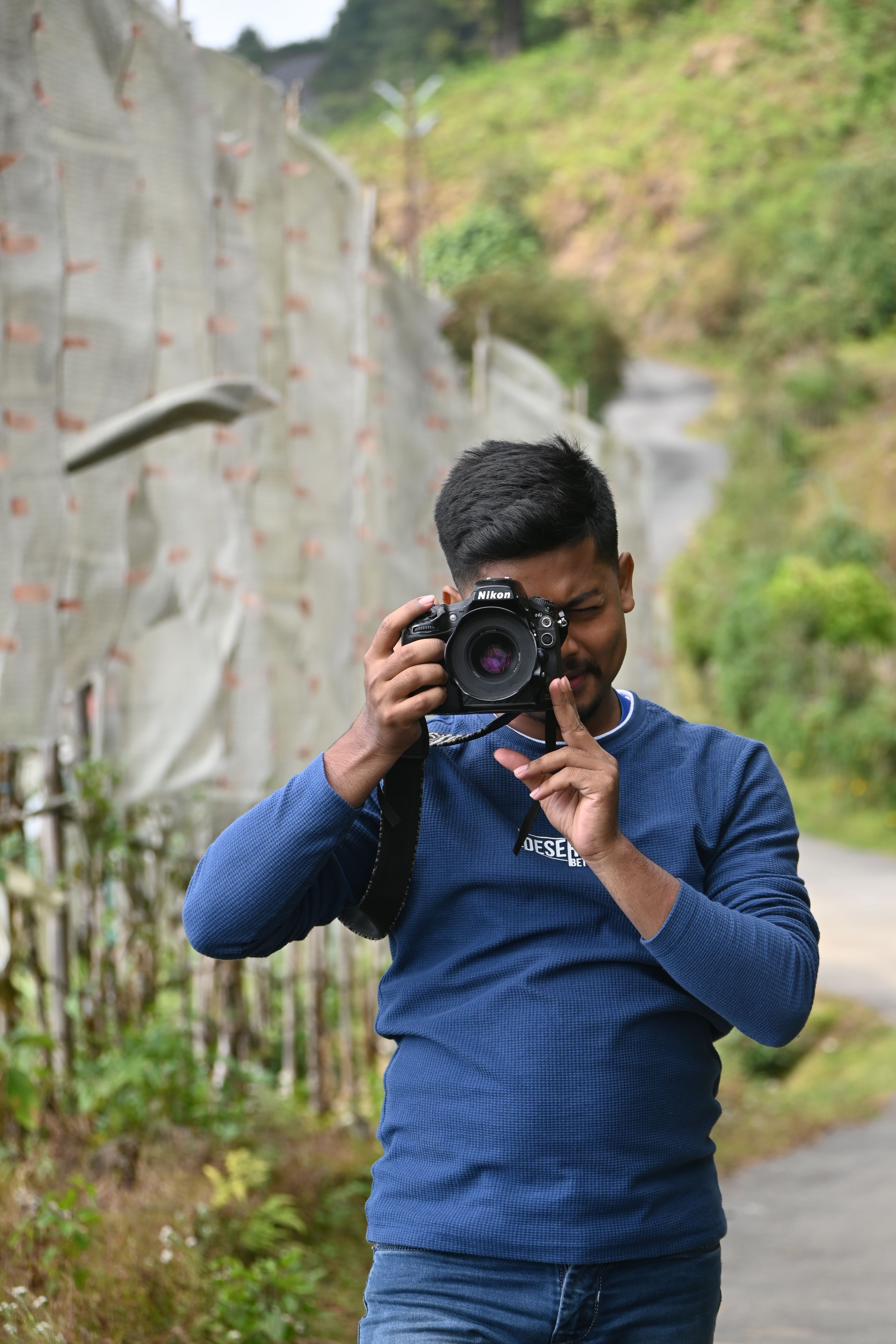 Young man takes pictures outdoors in Kalimpong, India, showcasing nature.