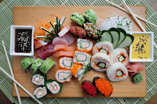 Free A colorful array of sushi rolls with sauces on a wooden board, perfect for food enthusiasts. Stock Photo