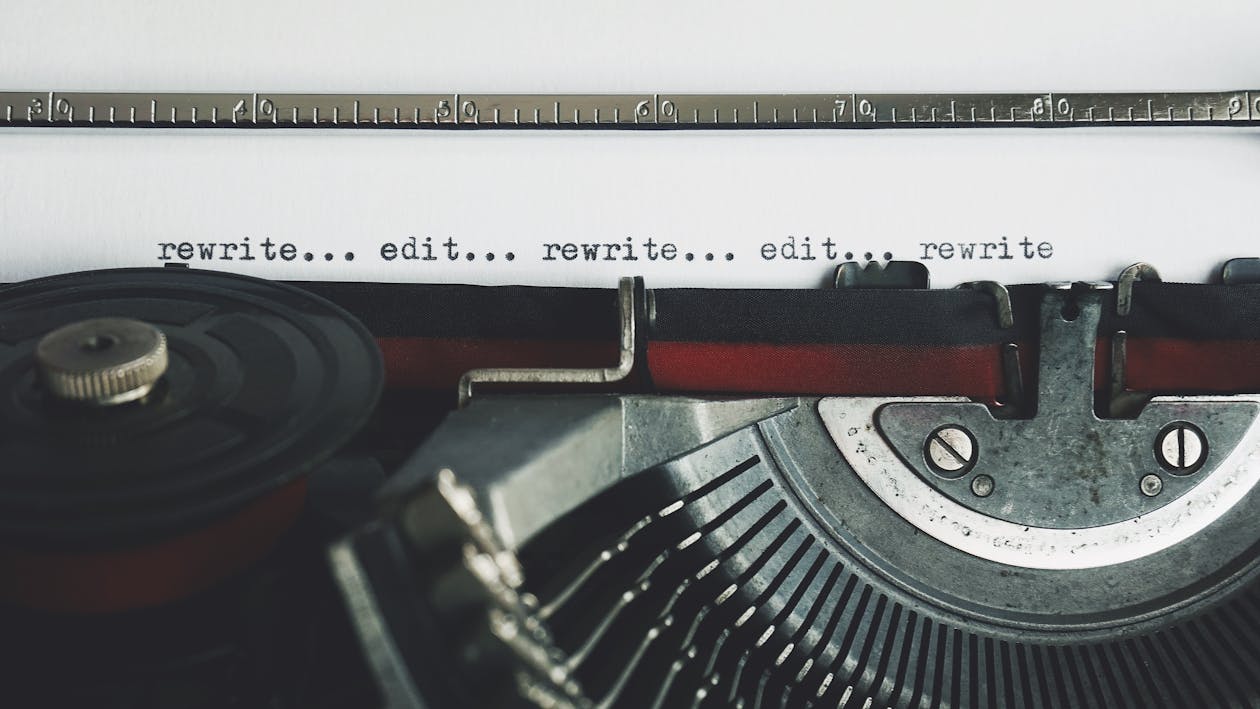 Vintage typewriter with text 'Write Edit Rewrite Repeat' on paper, symbolizing the self-publishing process of writing, editing, and revising a manuscript.