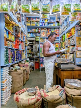 A busy Indian grocery store with a man checking stock amidst colorful products.
