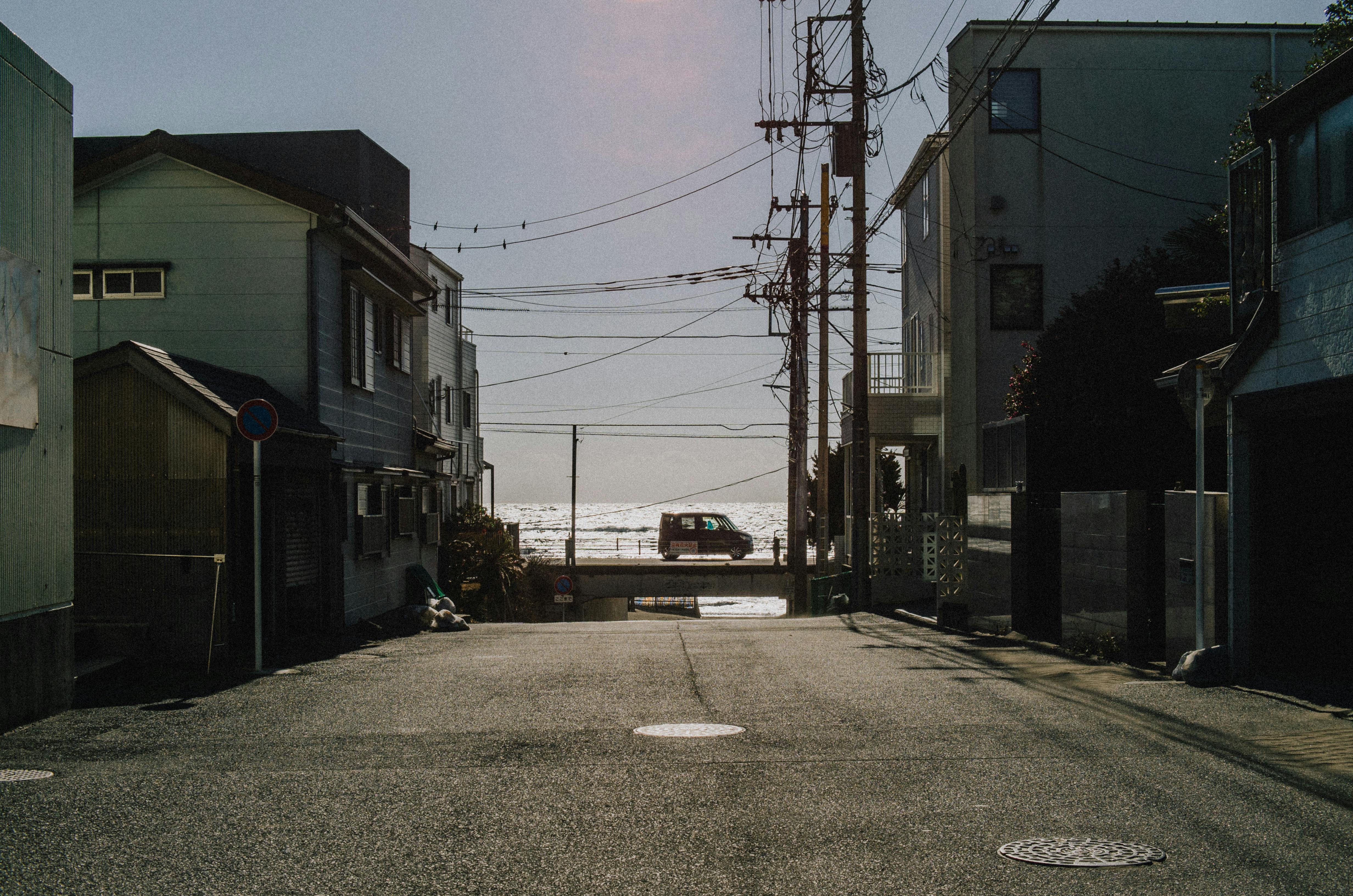 Free A quiet street in Kamakura, Japan, opens up to a stunning ocean view, capturing urban tranquility. Stock Photo