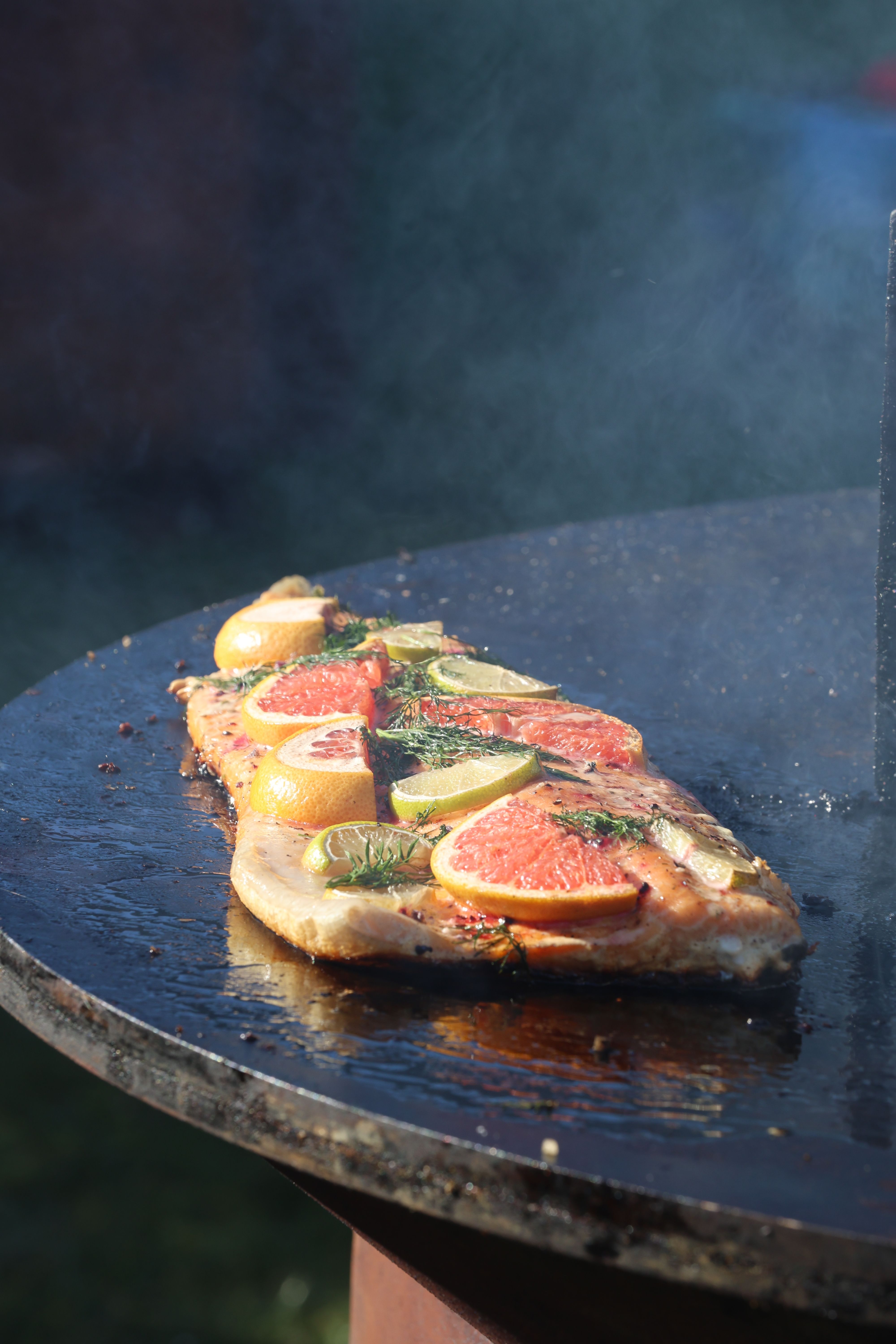Delicious grilled salmon with citrus slices on an outdoor grill in natural light.