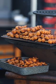 Appetizing grilled meat skewers arranged on a charcoal grill at an outdoor food market.