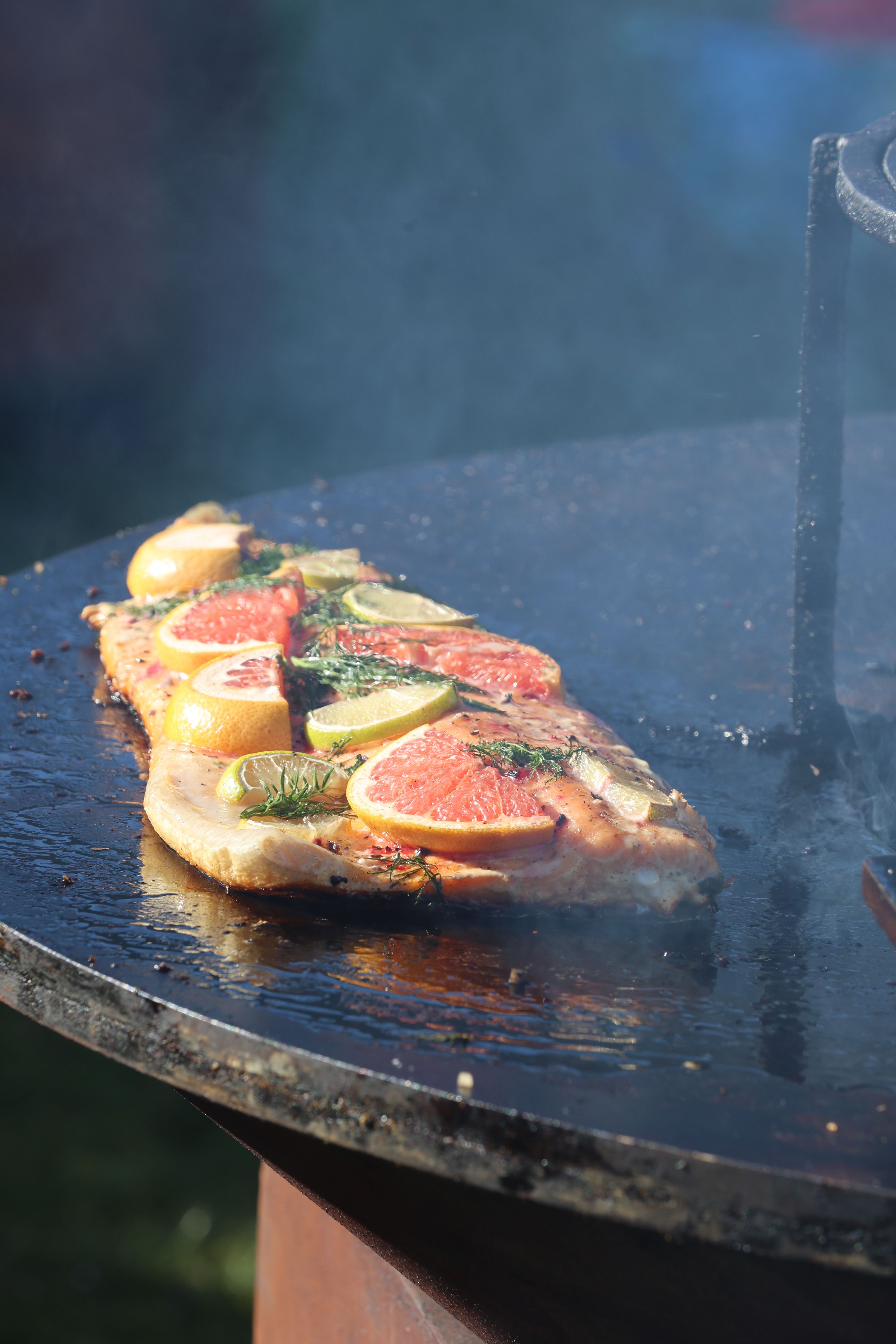 Delicious fish grilling topped with citrus slices, perfect for outdoor cooking.