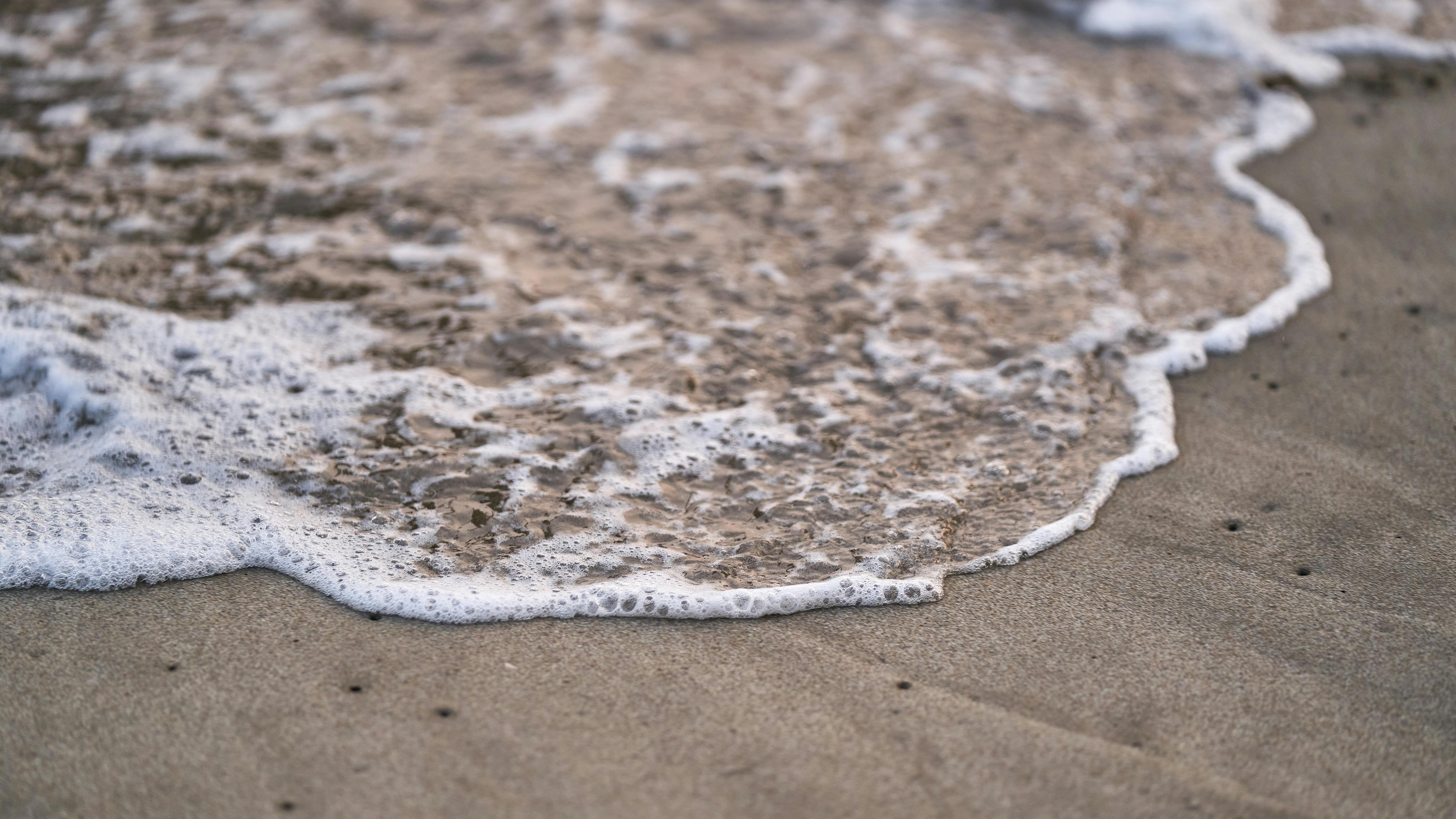Gratis Primo piano di una dolce onda dell'oceano che si infrange sulla riva sabbiosa della spiaggia. Foto a disposizione