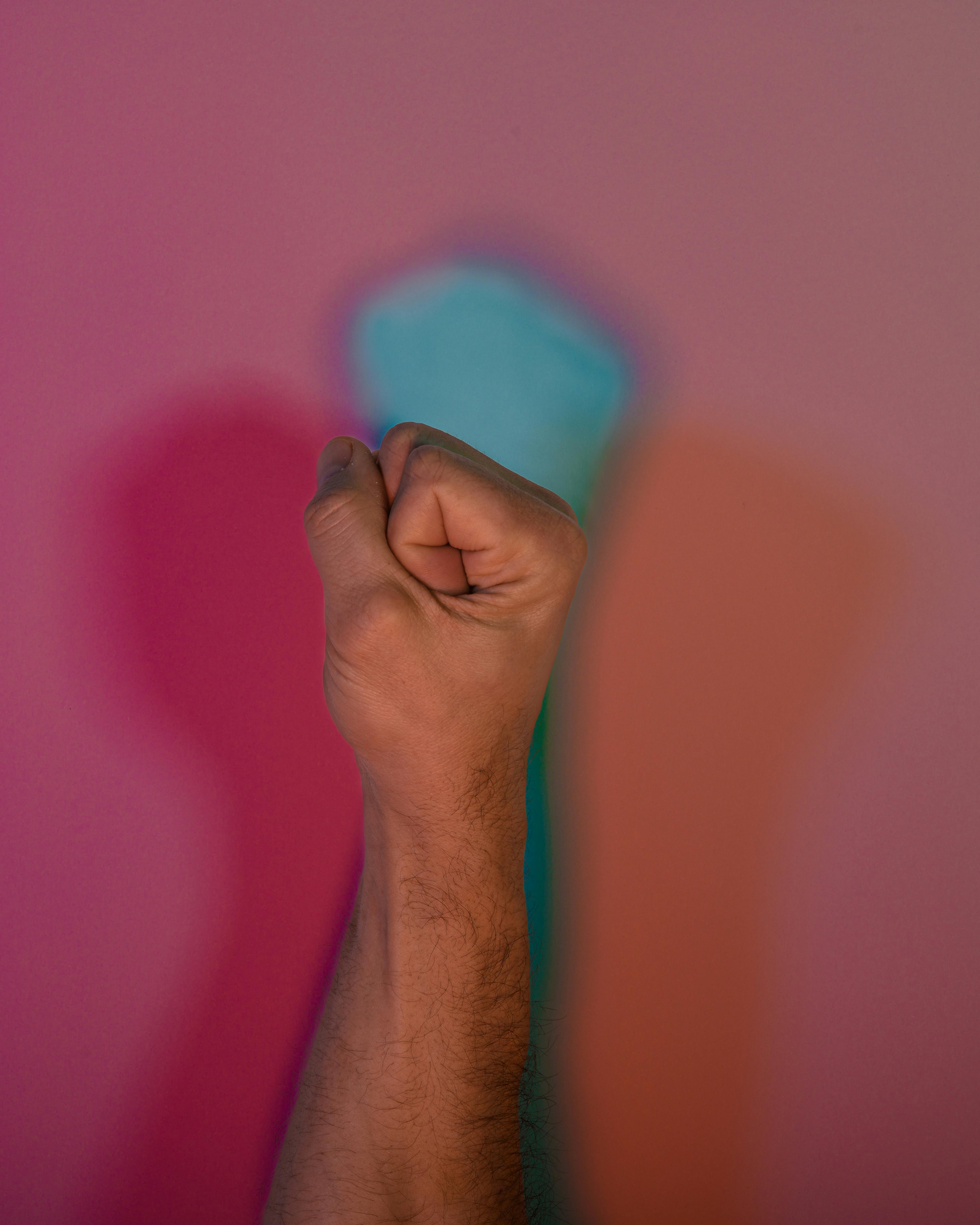 Gratis Un pugno alzato che proietta ombre colorate su uno sfondo vivace simboleggia forza e unità. Foto a disposizione