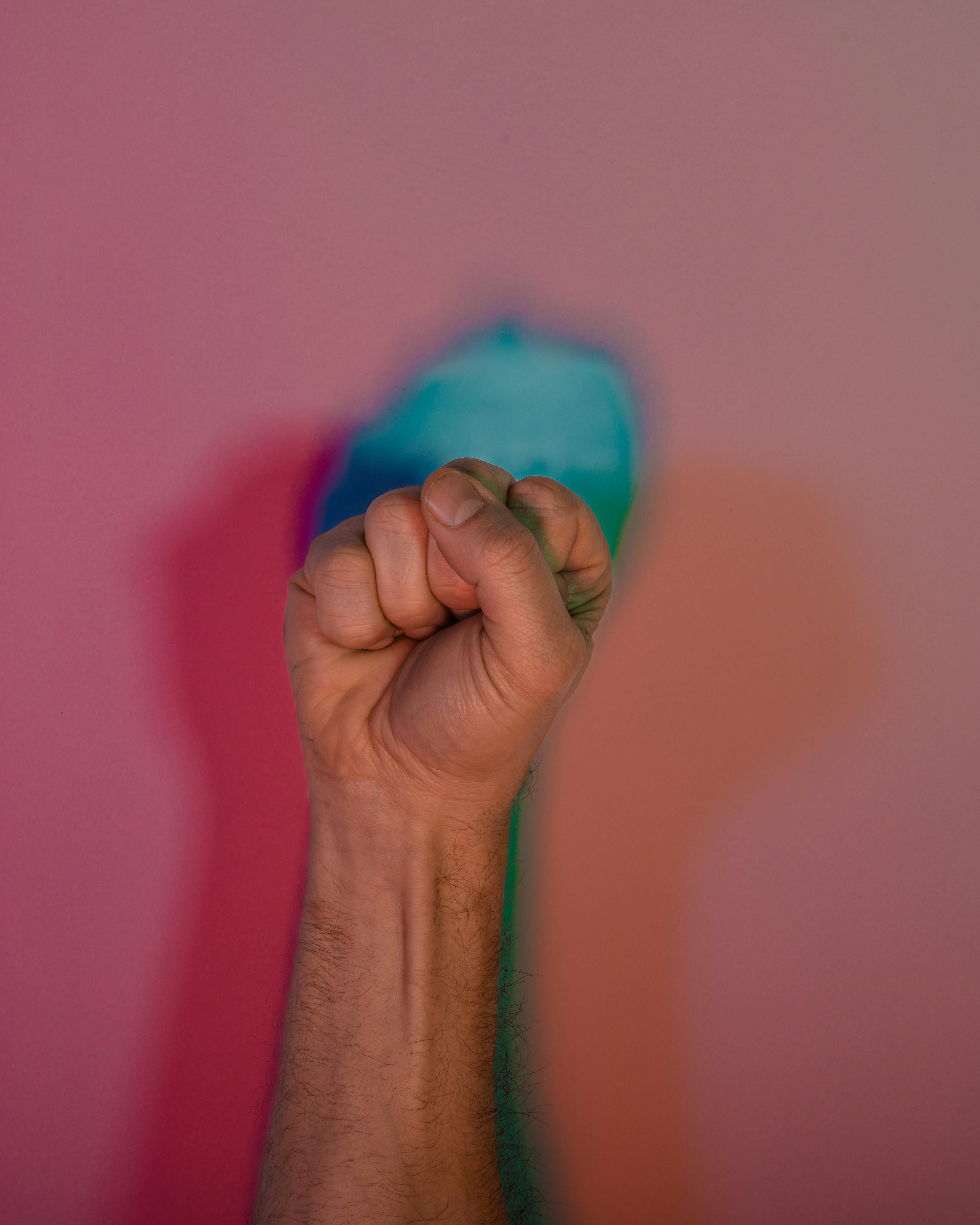 Ücretsiz Pembe bir zemin üzerinde canlı, çok renkli gölgelerle oluşturulmuş yumruk, gücü ve birliği simgeliyor. Stok Fotoğraflar