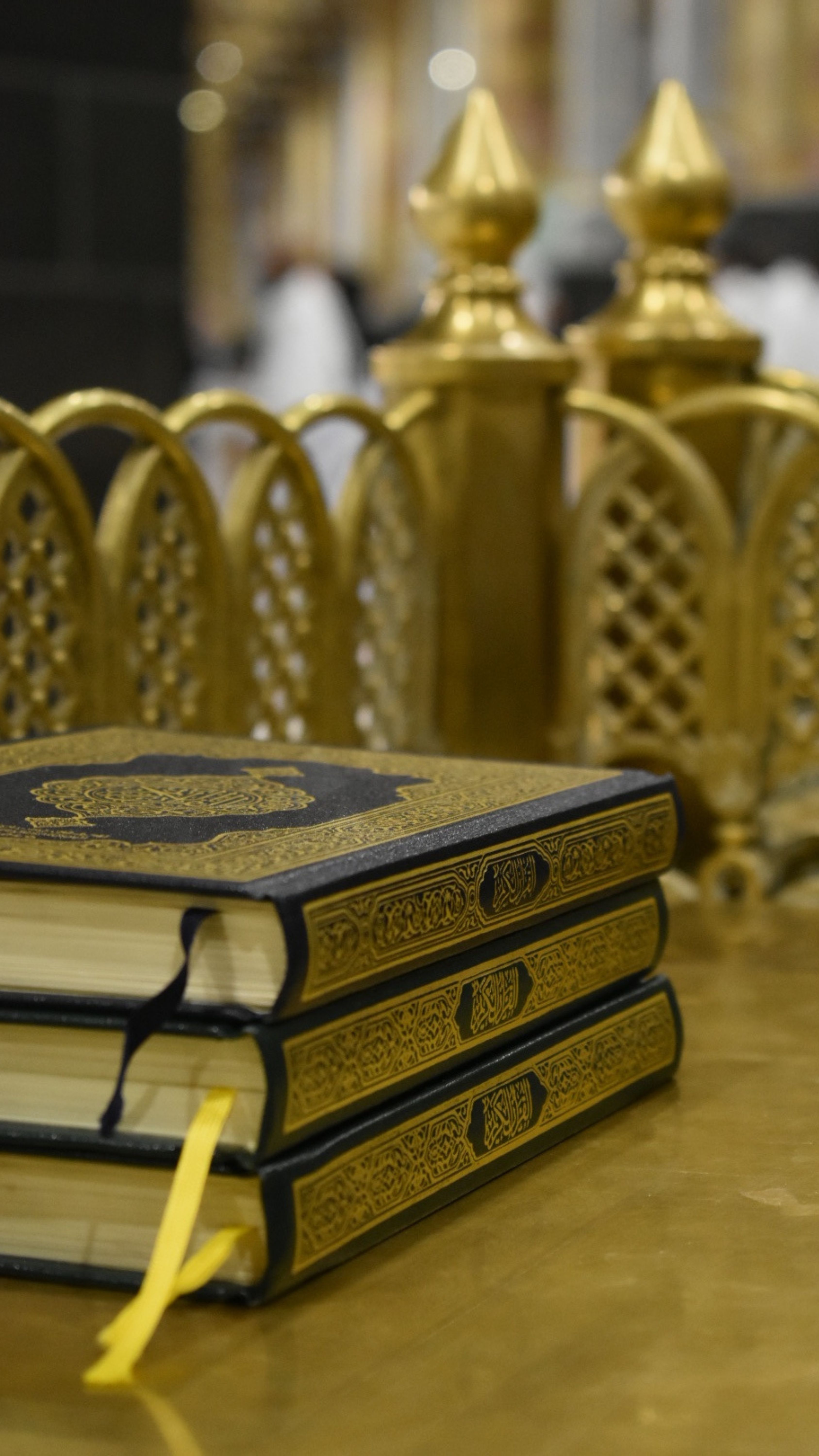 Close-up of a stack of Quran books with a decorative golden background, reflecting religious reverence.