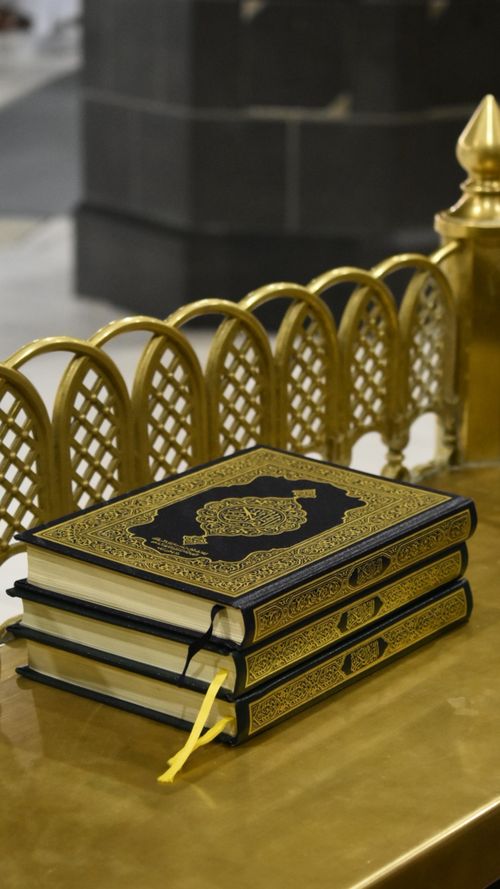 Free Three Qurans stacked with ornate gold designs, symbolizing faith and spirituality. Stock Photo