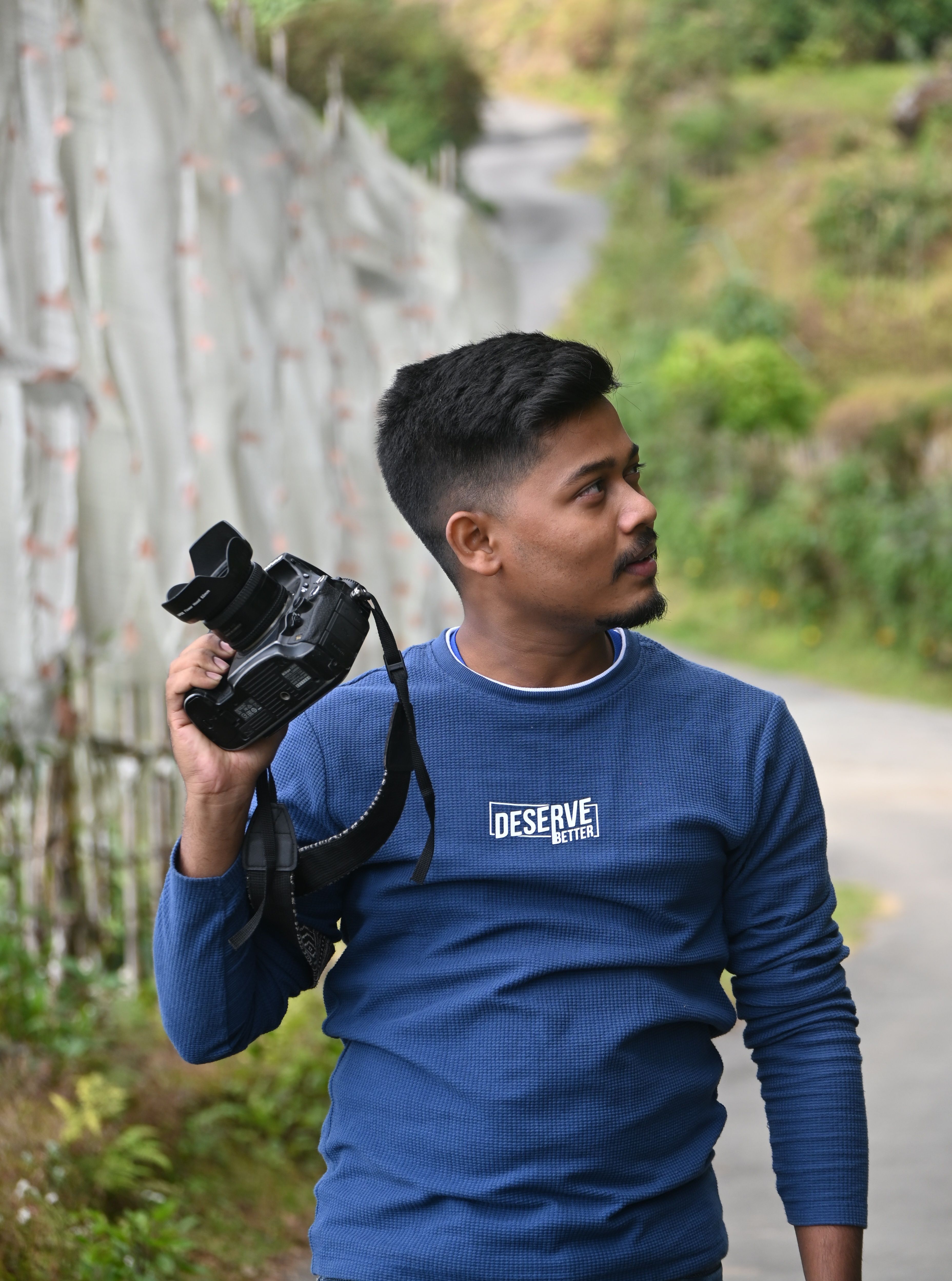 Young male photographer holding a camera in scenic Kalimpong, India.