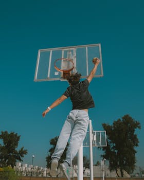 Athlete performing exciting slam dunk on outdoor basketball court in León, Mexico.