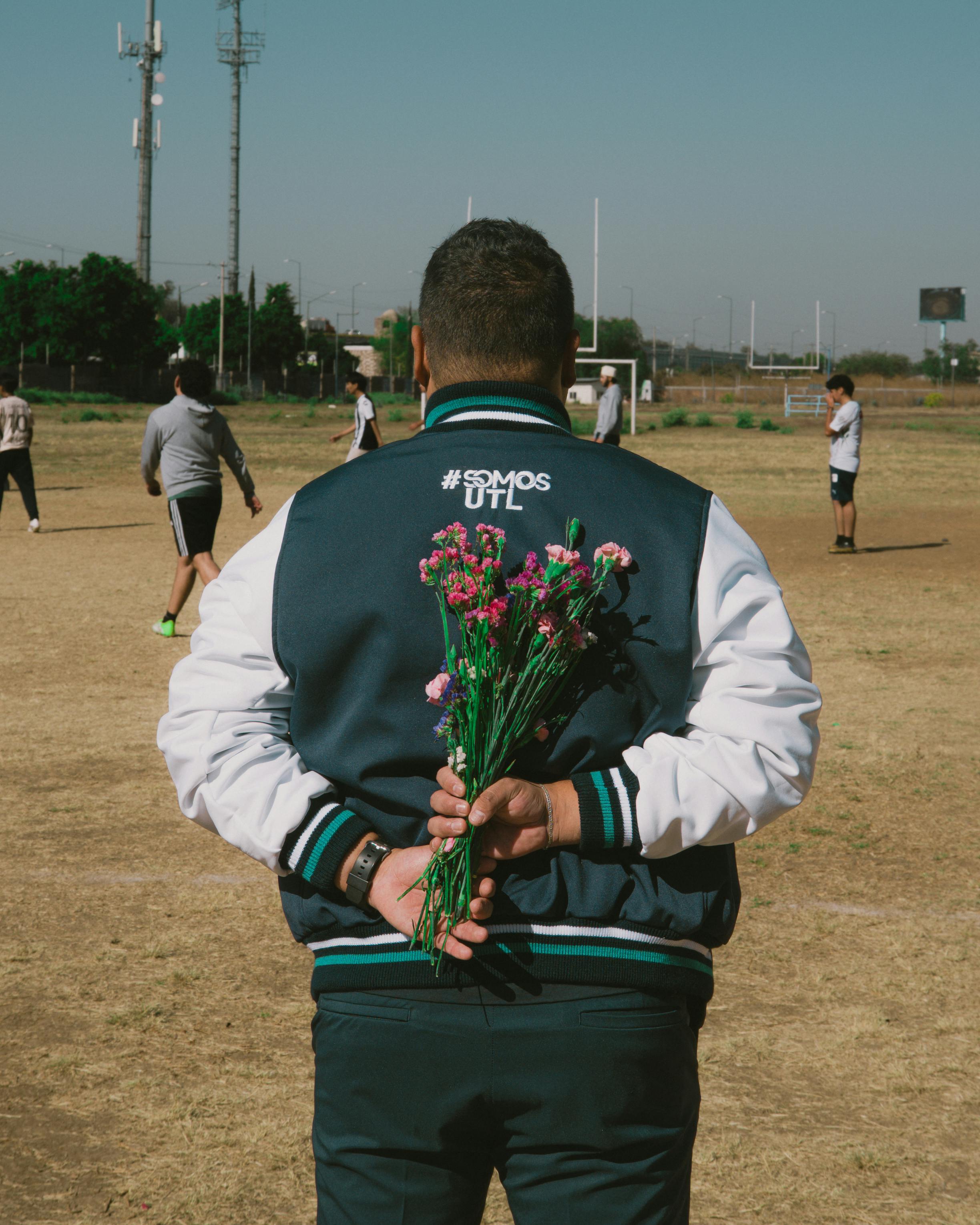 Ücretsiz Meksika'nın León kentindeki bir spor sahasında elinde çiçek olan bir adam, şaşkın bir ifadeyle bakıyor. Stok Fotoğraflar