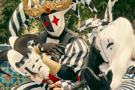 Vibrant harlequin costumes and masks at a lively outdoor carnival setting.