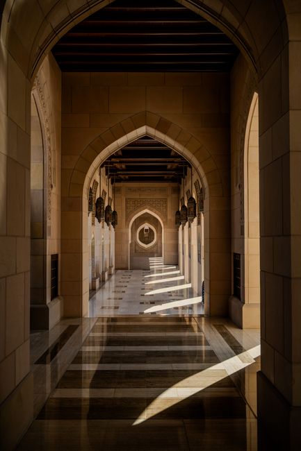 A stunning architectural corridor featuring intricate arches and shadows in Muscat, Oman.