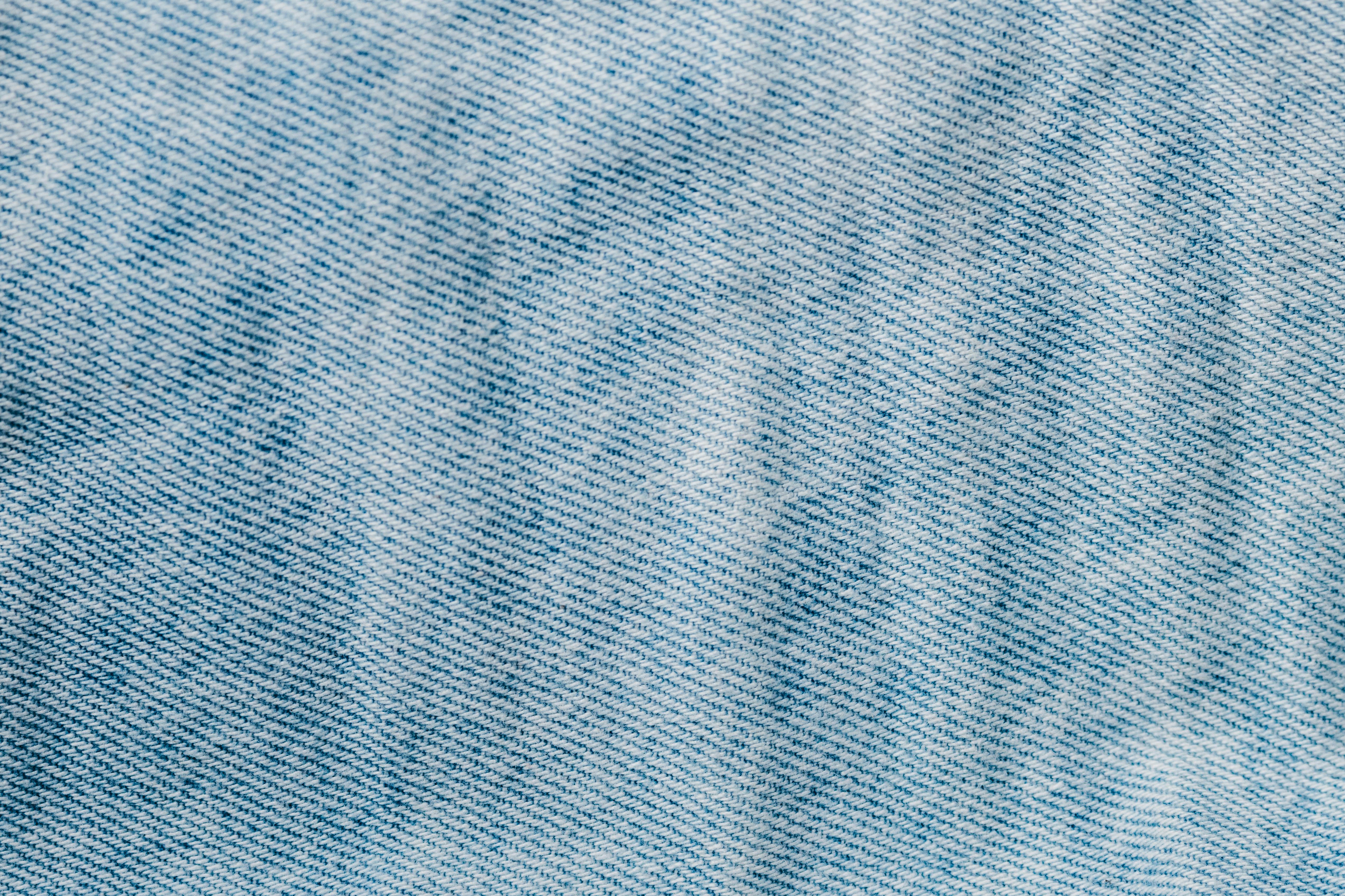 бесплатная Детальный крупный план светло-голубой джинсовой ткани, демонстрирующий текстуру и рисунок плетения. Стоковое фото