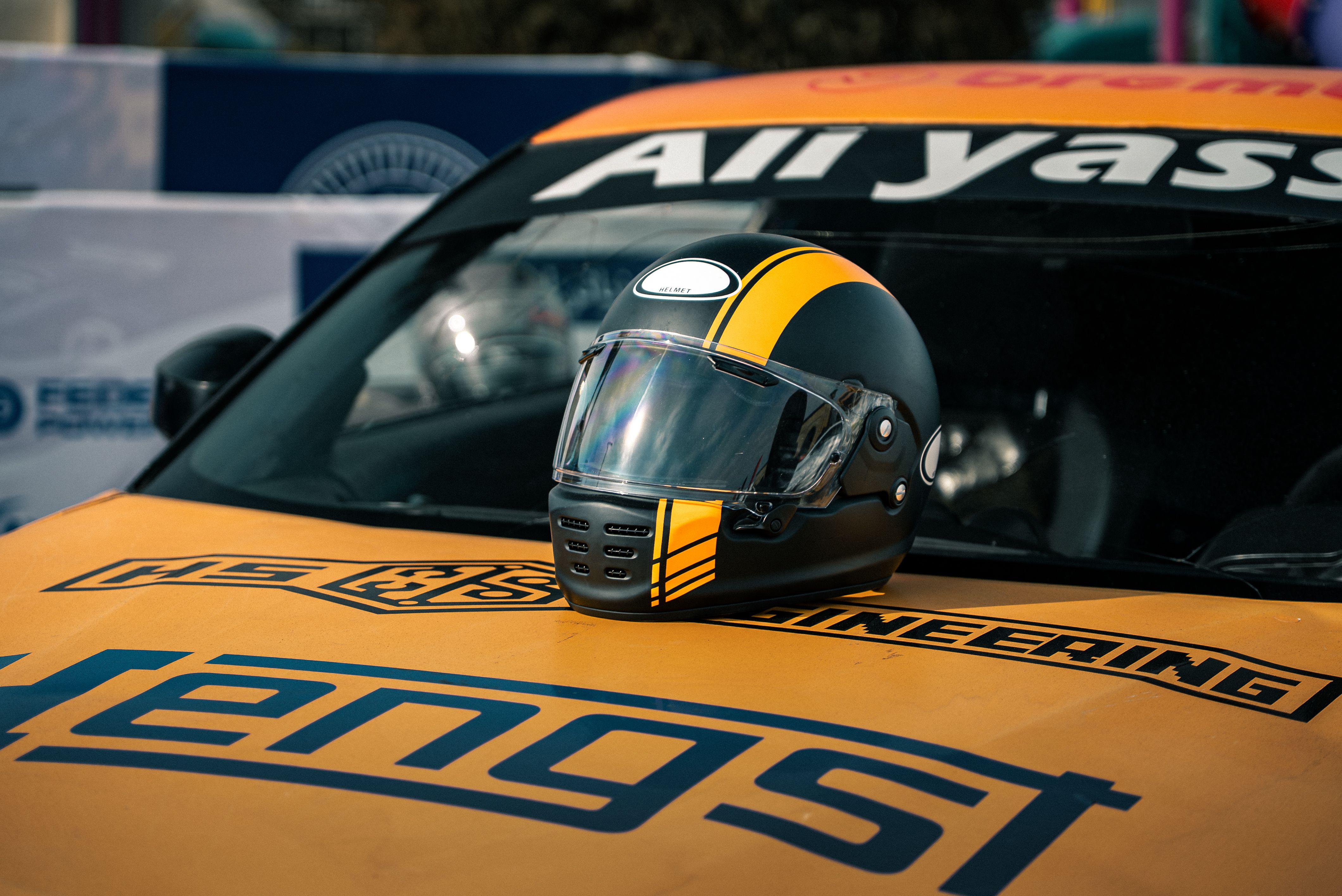 Close-up of a racing helmet on a sports car hood during a sunny day in Erbil, Iraq.