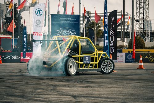Free A yellow drift car performing a smoke-emitting stunt during a motorsport event in Erbil, Iraq. Stock Photo