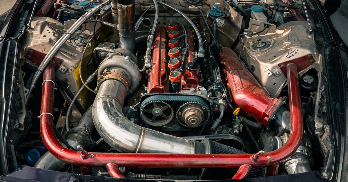 Detailed view of a modified car engine with red accents, showcasing its components.