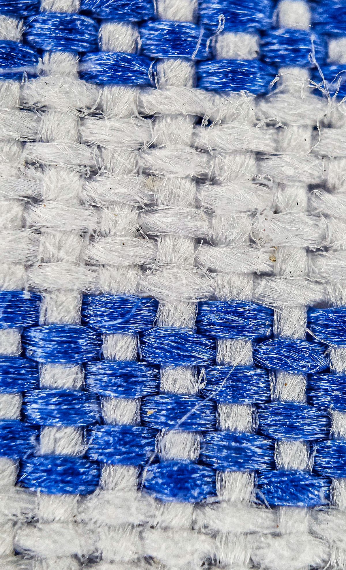 Close-up of a woven fabric structure with blue and white warp and weft yarns interlaced