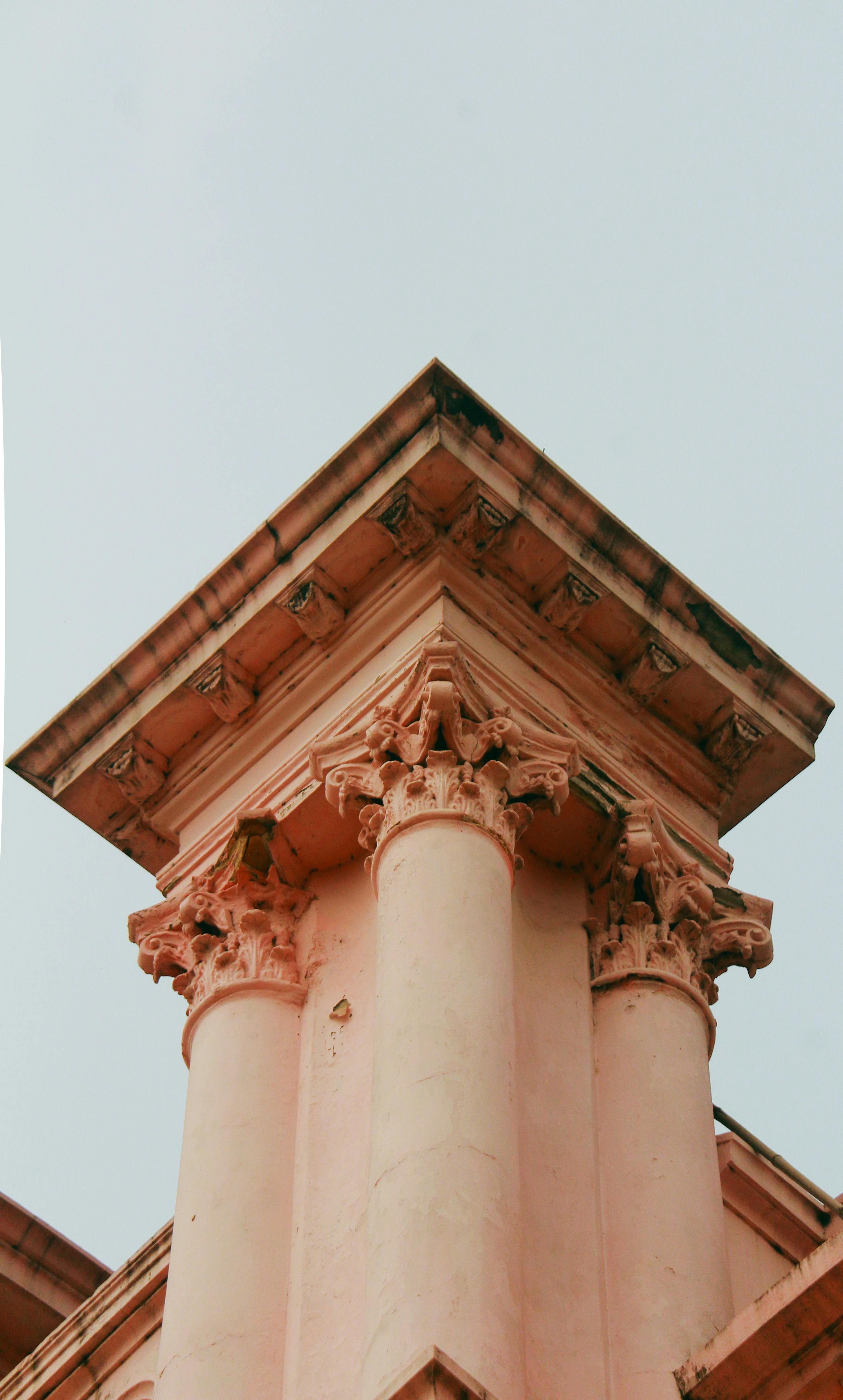 De franc Primer pla d'elegants columnes clàssiques amb capitells ornamentats contra un cel clar, que destaquen la bellesa arquitectònica. Foto d'estoc
