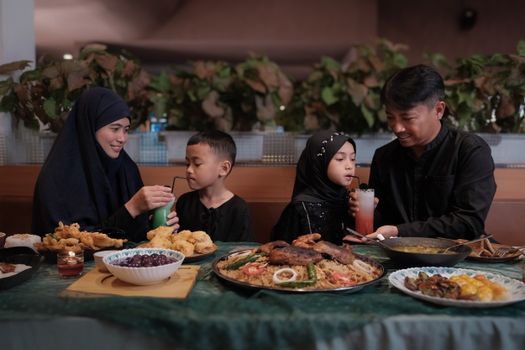 A family of four enjoys a meal in Bandung, showcasing traditional attire and delicious food.