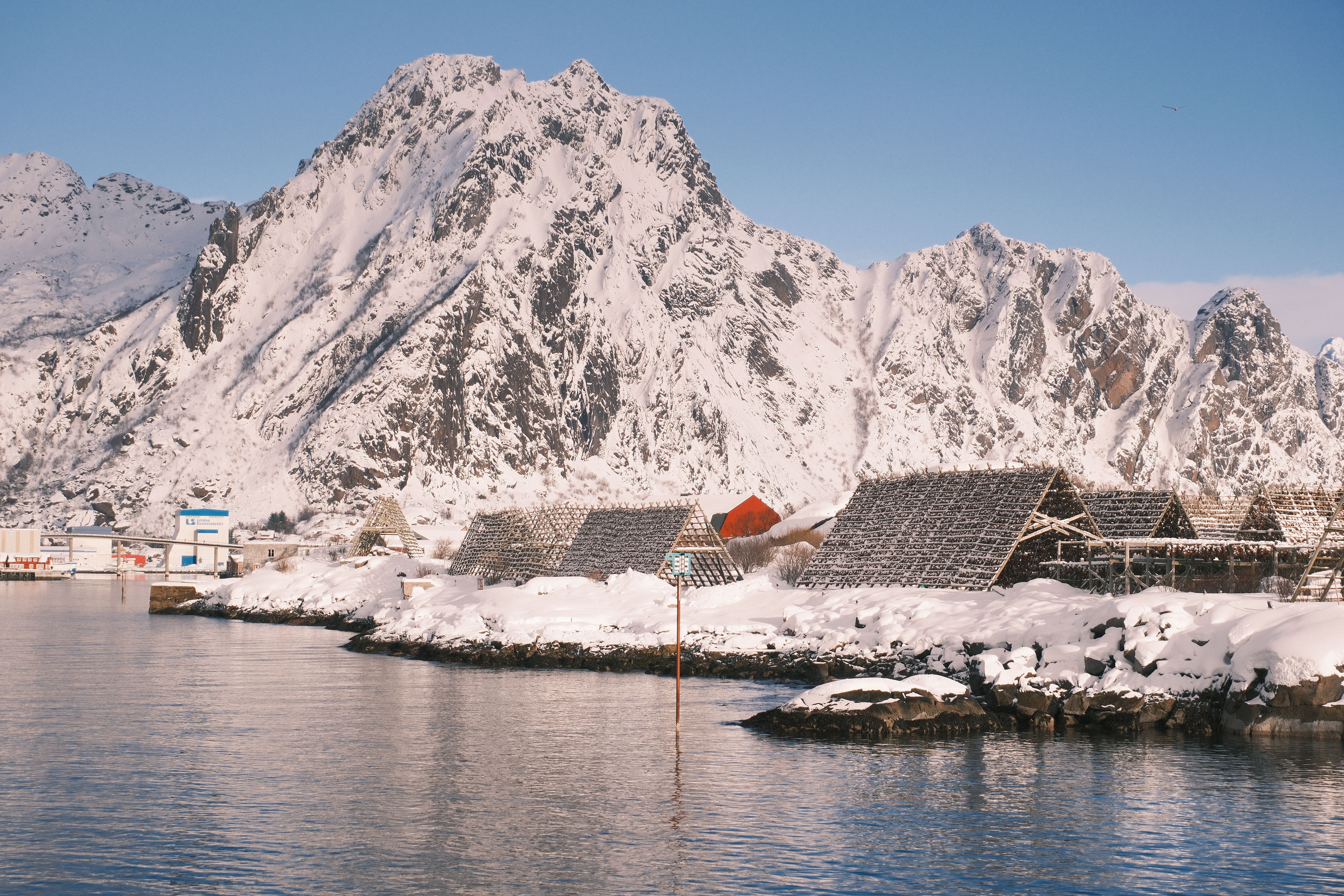 Captivating winter landscape of snow-covered Svolvær, Norway, showcasing traditional Fishermen's huts against mountainous backdrop.
