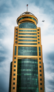 Stunning view of a golden skyscraper in Kuwait City with an airplane in the sky.