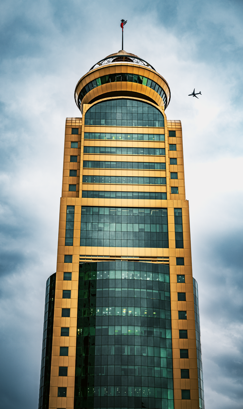 Free Stunning view of a golden skyscraper in Kuwait City with an airplane in the sky. Stock Photo