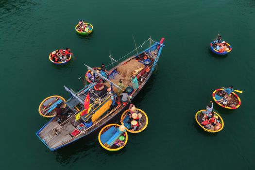 Colorful traditional fishing boats and fishermen on the ocean captured from above.