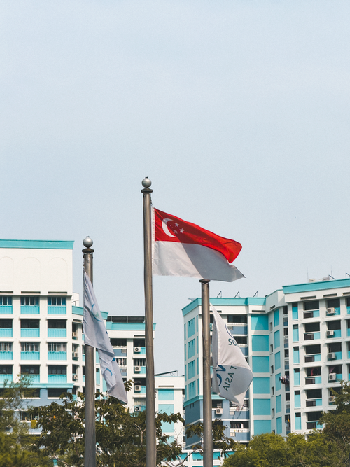 Free Singapore flag flies against urban residential skyline. Stock Photo