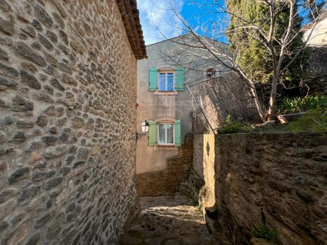 A quaint stone alley in Miramas, France, under clear blue skies