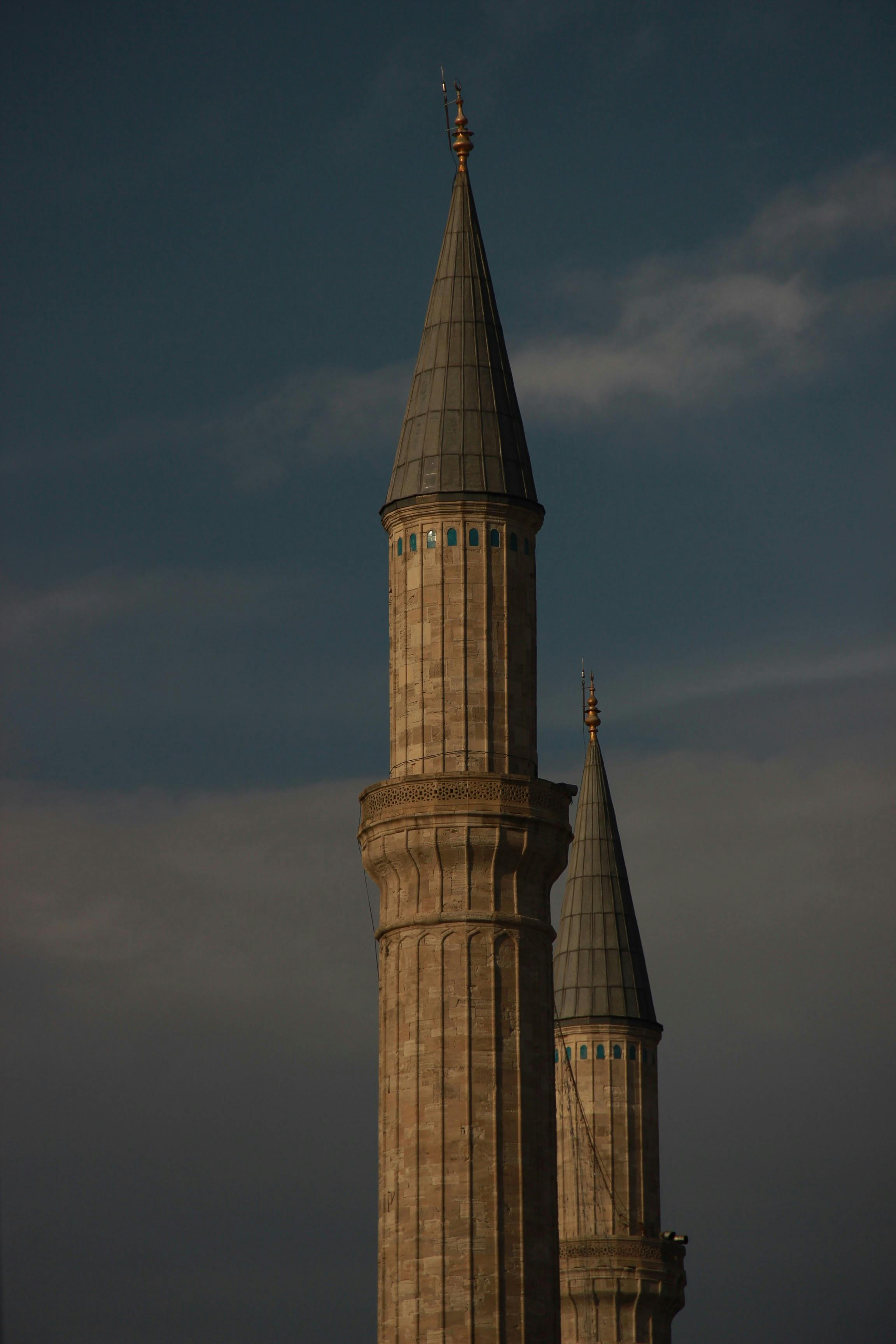 無料 曇り空の下、青い空に向かってそびえ立つモスクのミナレットの印象的な眺め。建築美をとらえています。 写真素材